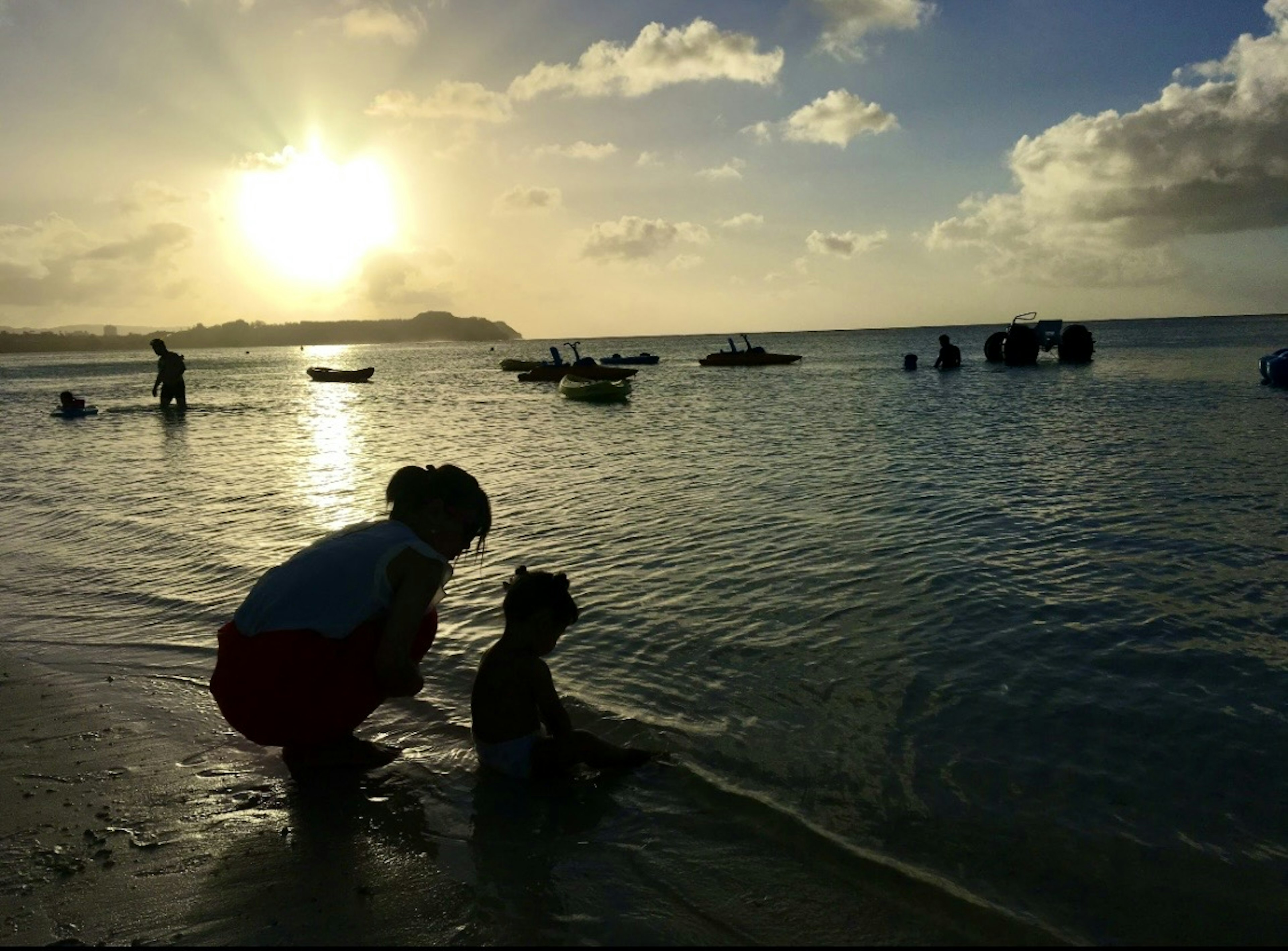 海辺で遊ぶ親子のシルエット、夕日、穏やかな水面