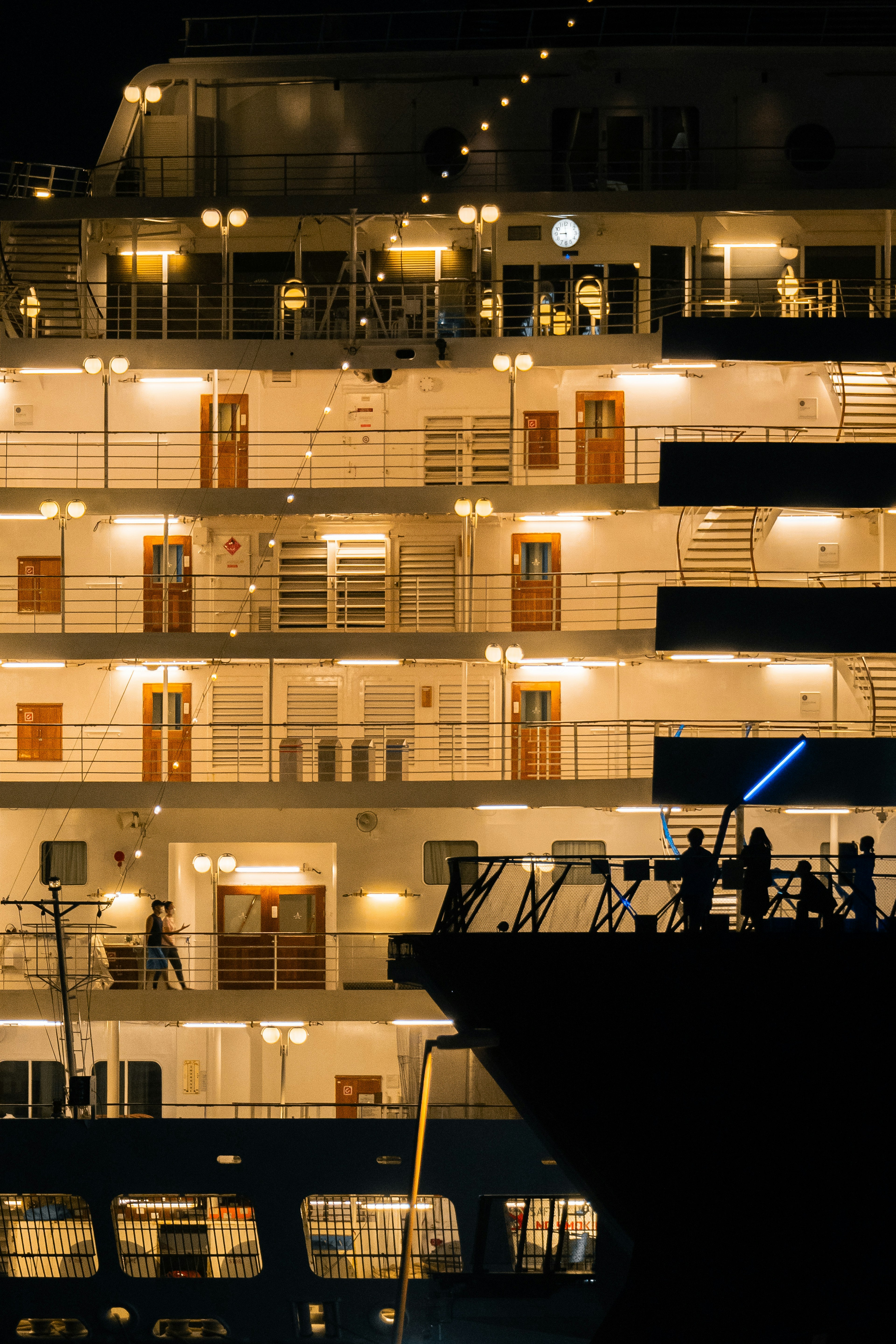 Ponts éclairés d'un navire de croisière la nuit avec des silhouettes de personnes