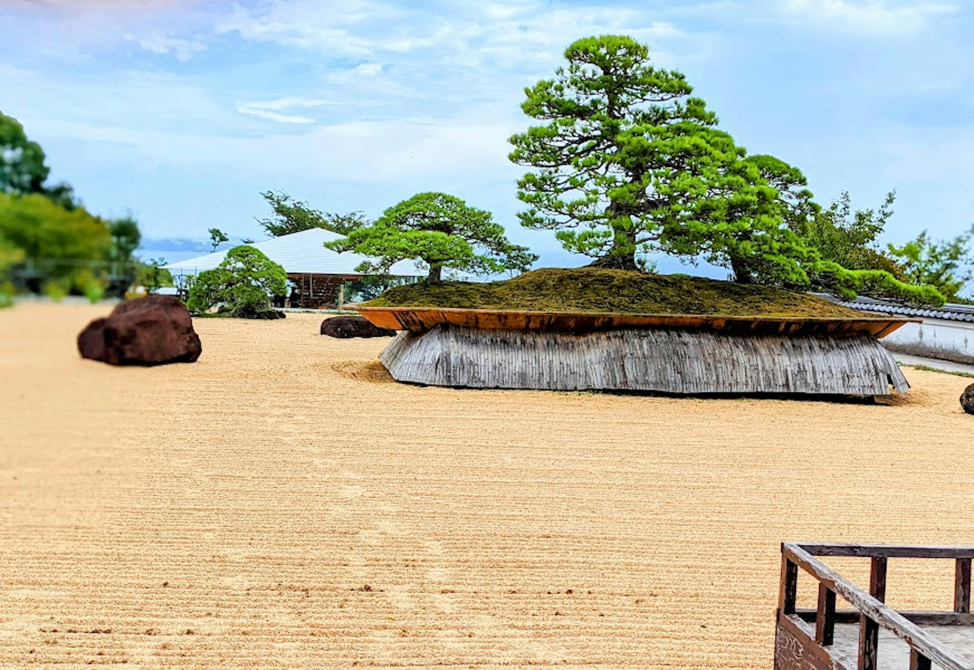 Un jardin de sable serein avec des rochers couverts de mousse et un pin