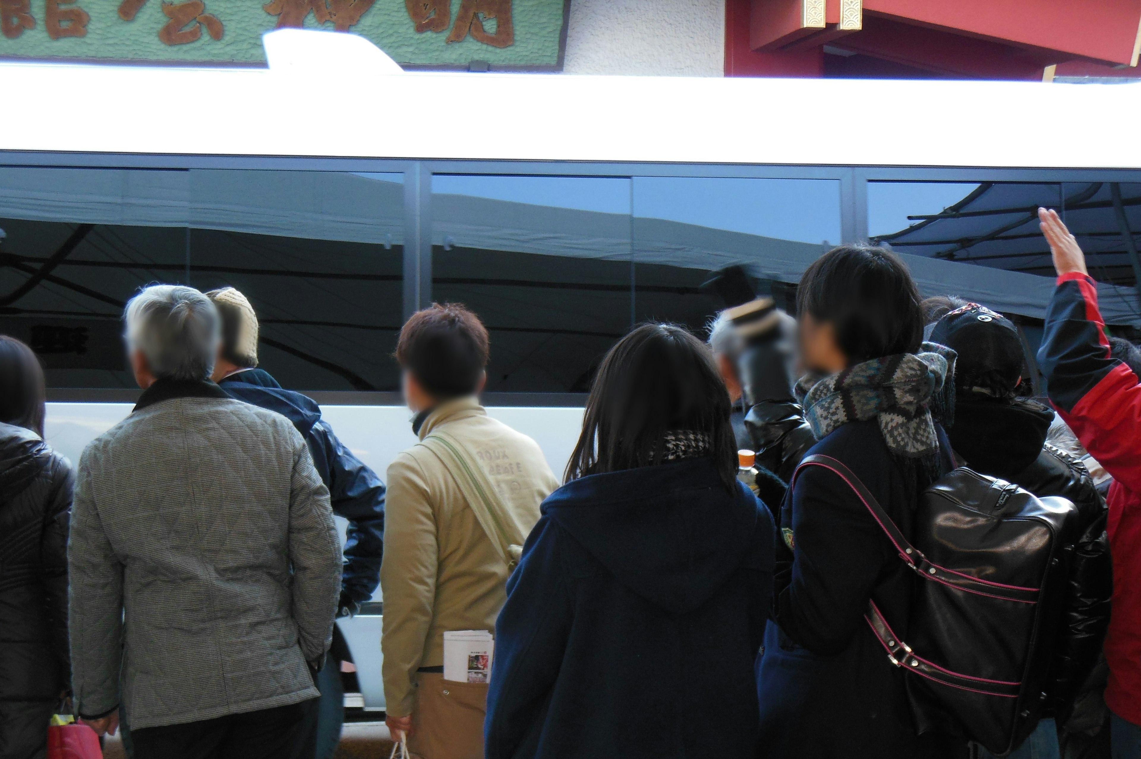 Un grupo de personas esperando en una estación de tren con un tren al fondo