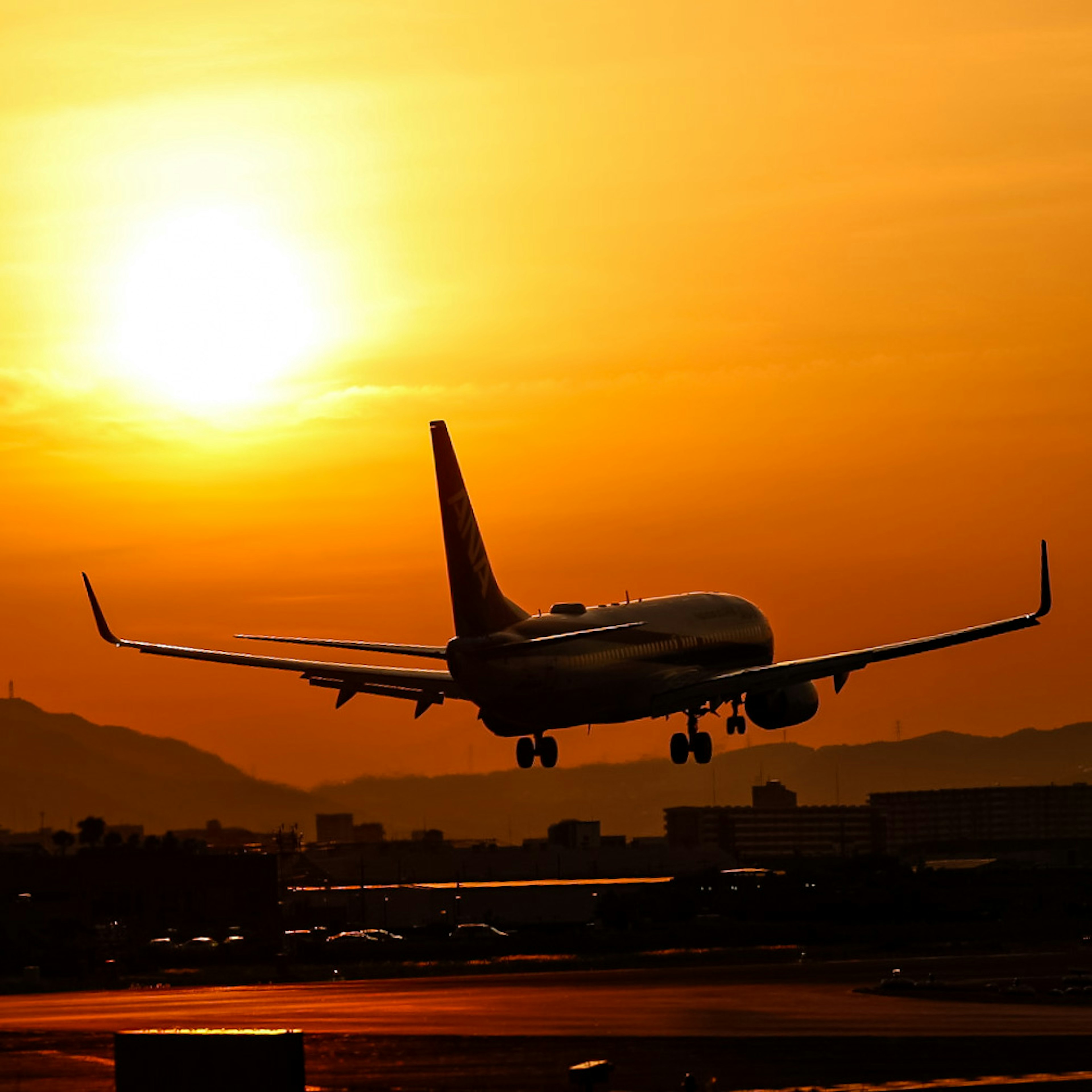 Airplane landing against a sunset backdrop