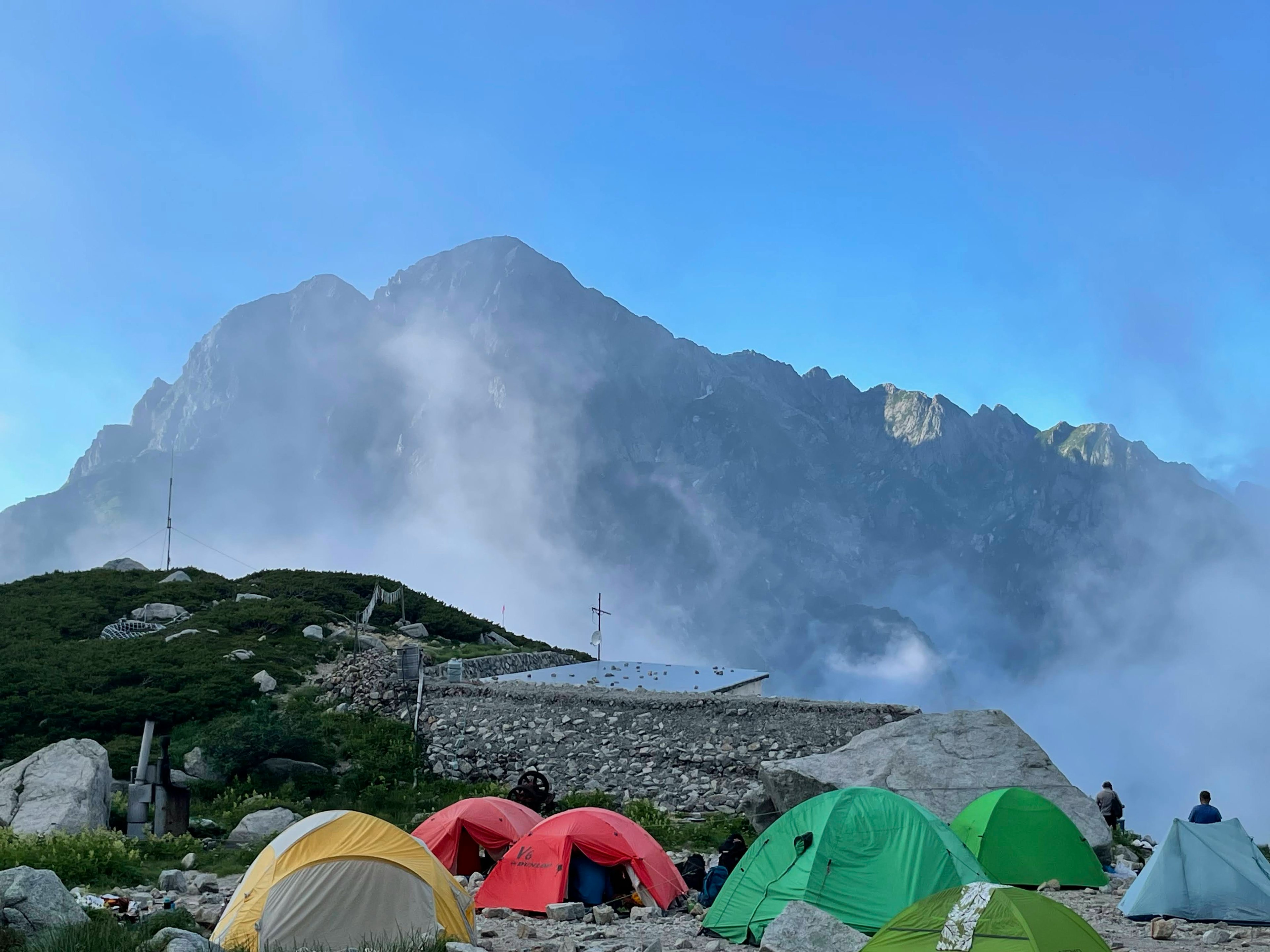 Colorful tents set against a mountainous backdrop under a clear blue sky