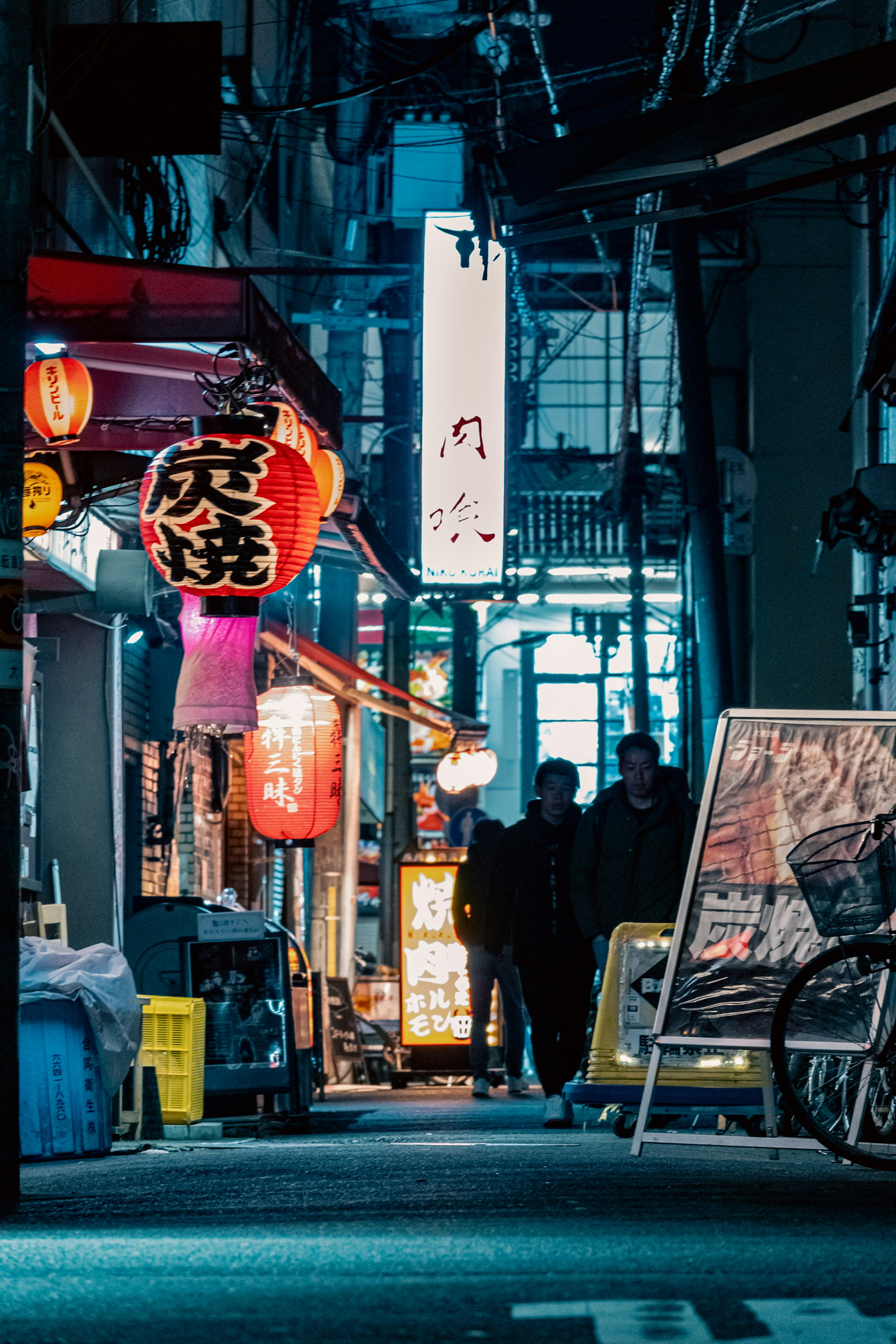 Night street scene with restaurants and silhouettes of people