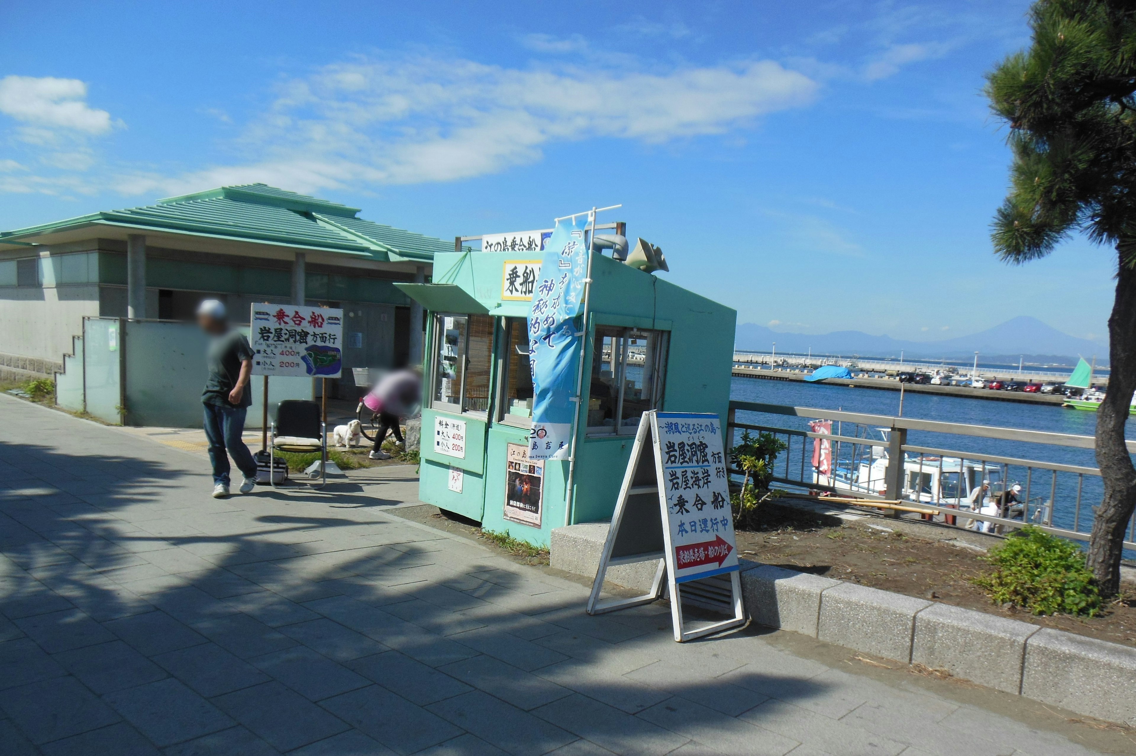 A blue kiosk near the sea with people approaching it