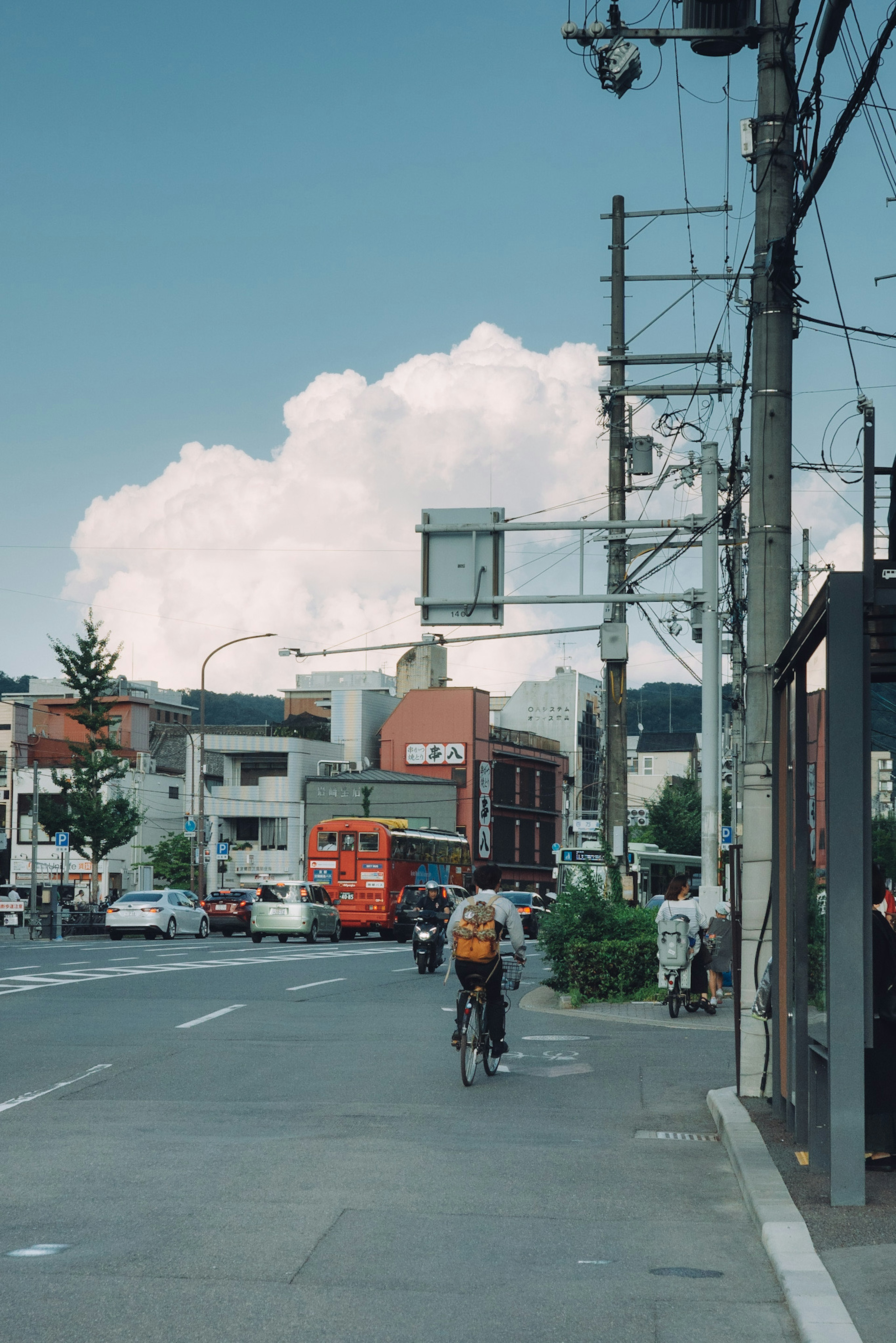 街景，骑自行车的人在蓝天和蓬松云朵下