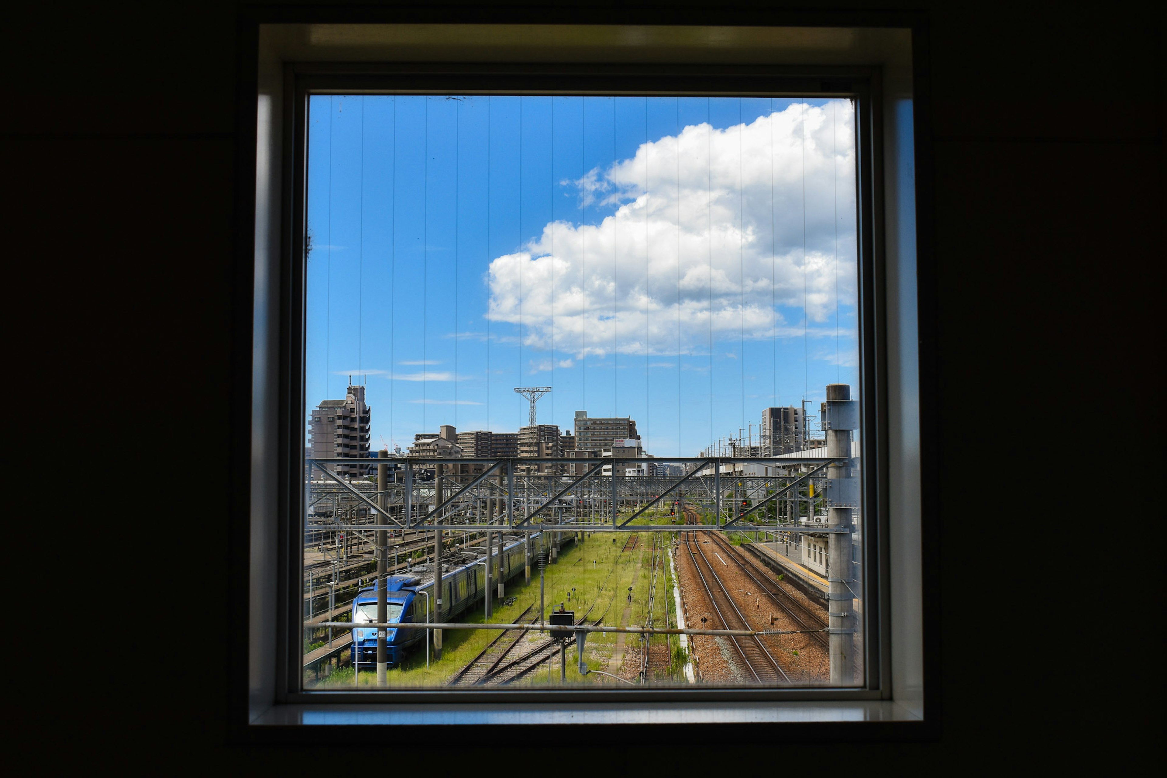 Cityscape view from a window with blue sky and clouds
