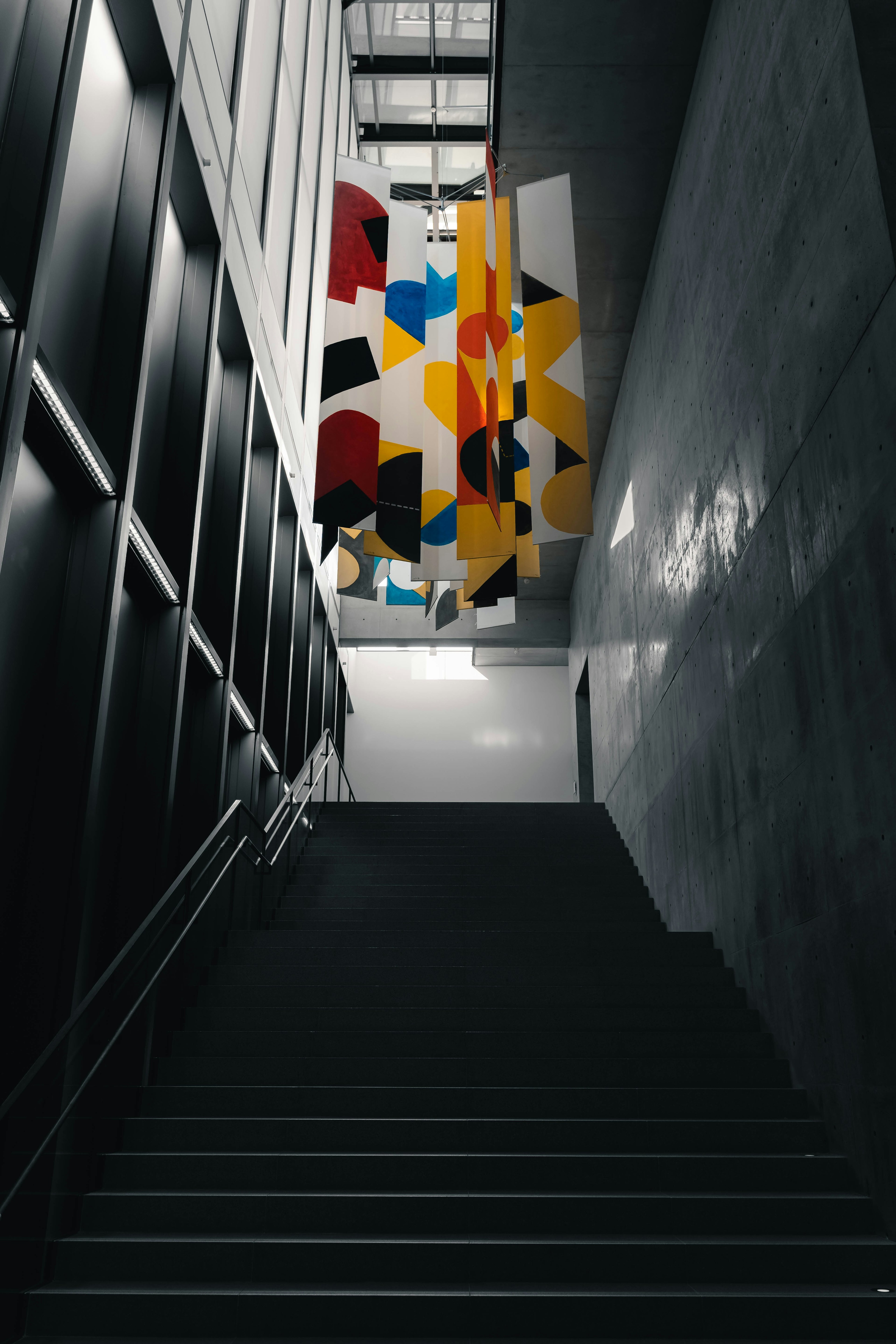 Modern art installation hanging above a staircase viewed from below