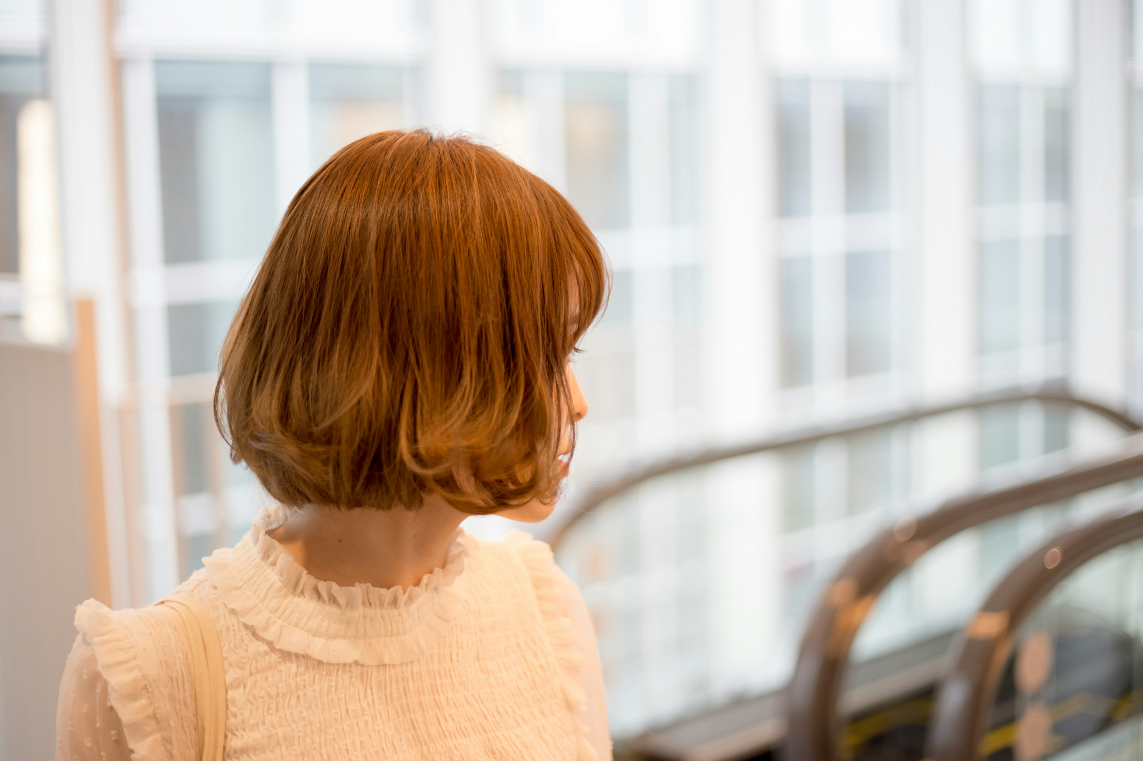 A woman with short brown hair standing sideways in a bright space