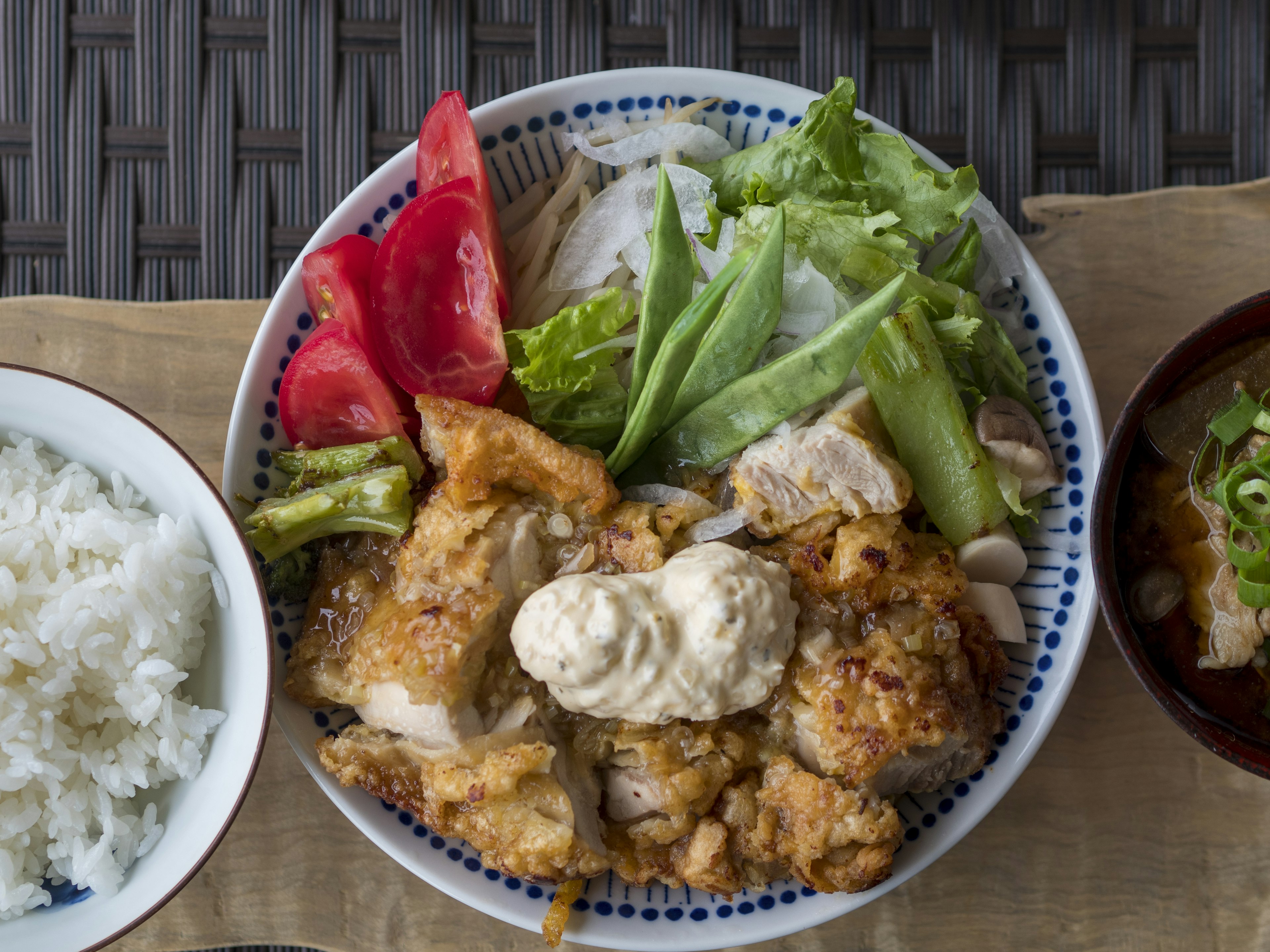 Piring dengan ayam goreng, salad, tomat, dan nasi