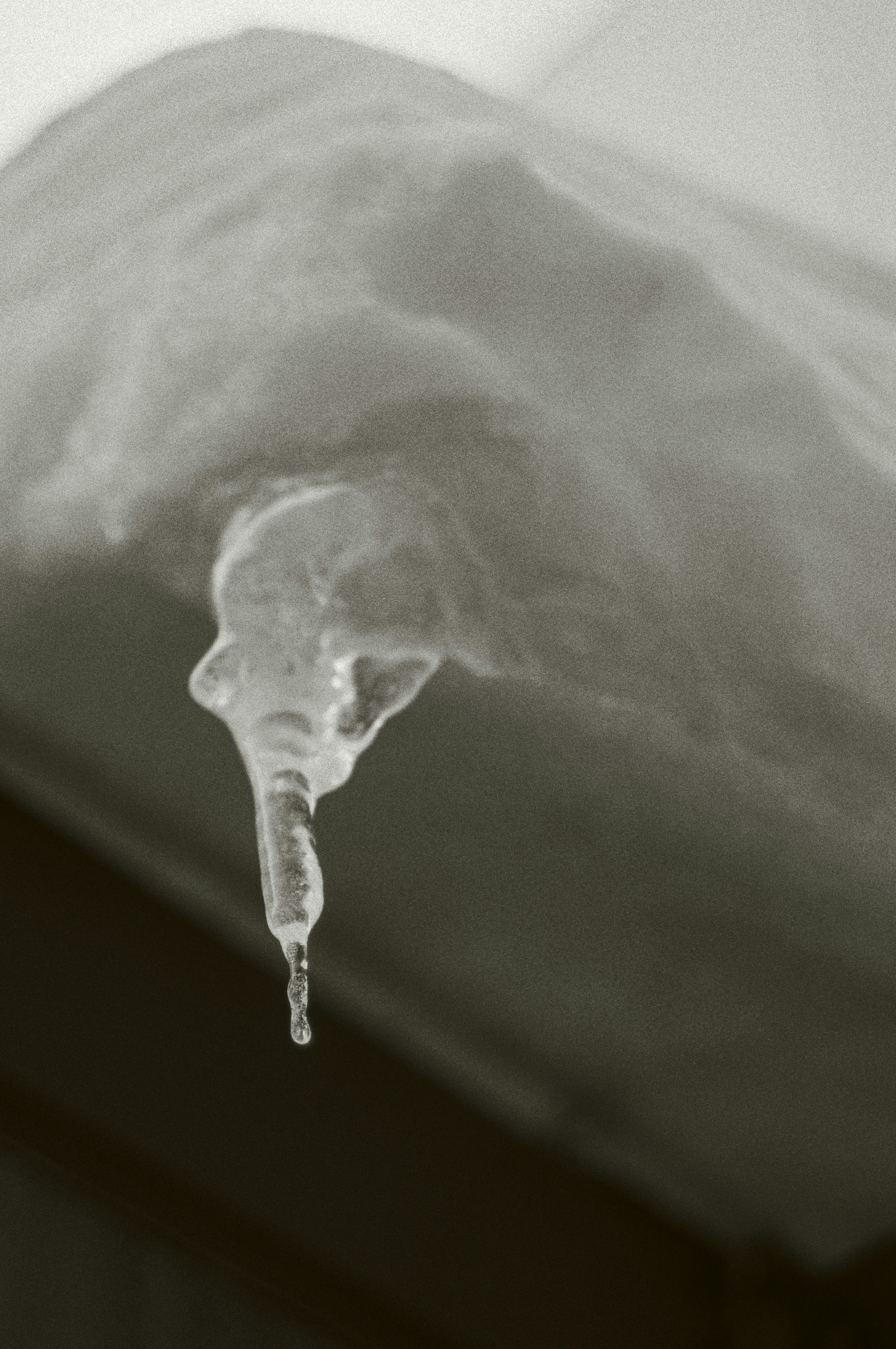 Icicle hanging from snow with a blurred background