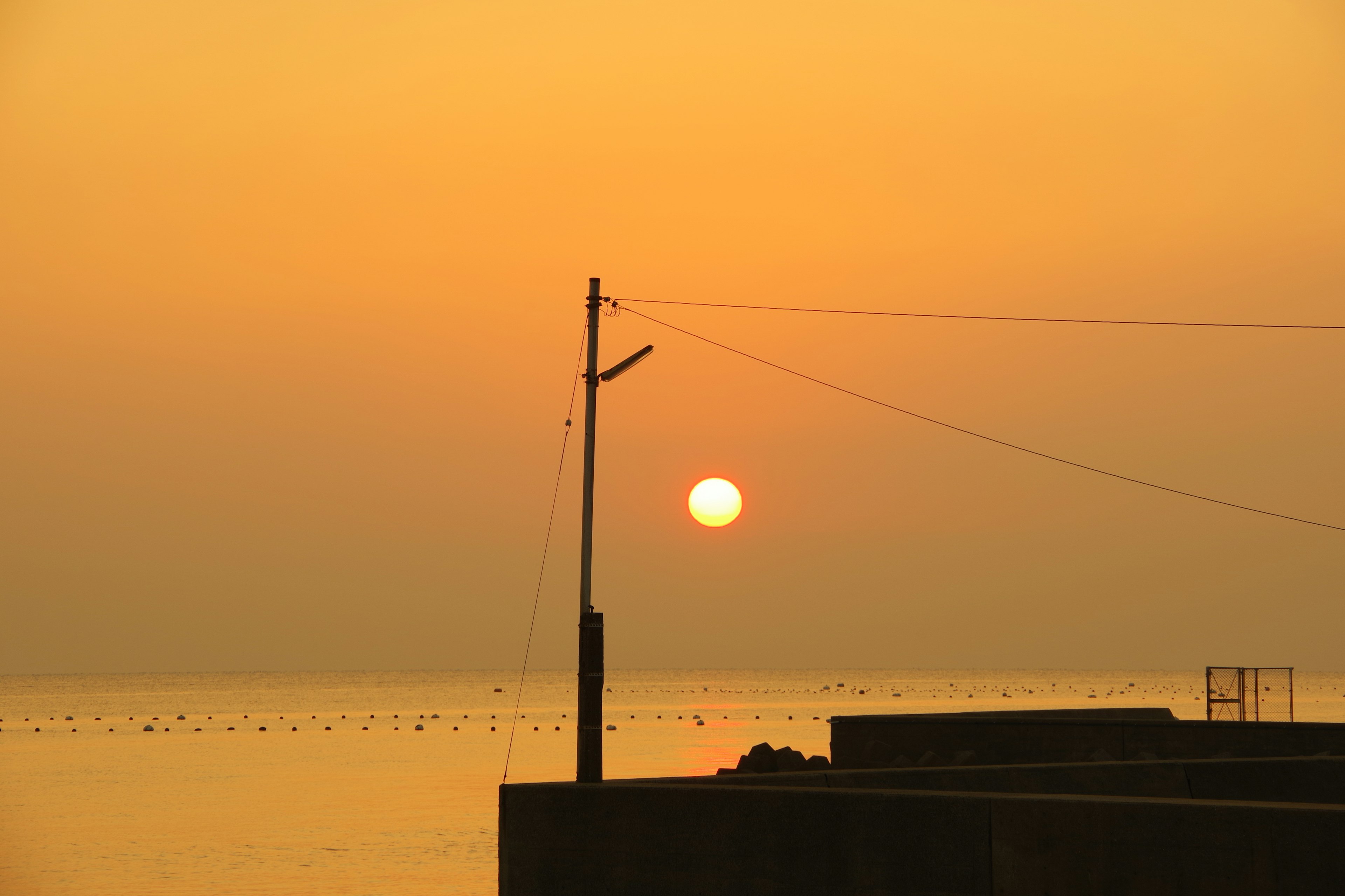 Sonnenuntergang über dem Meer mit der Silhouette eines Pfostens