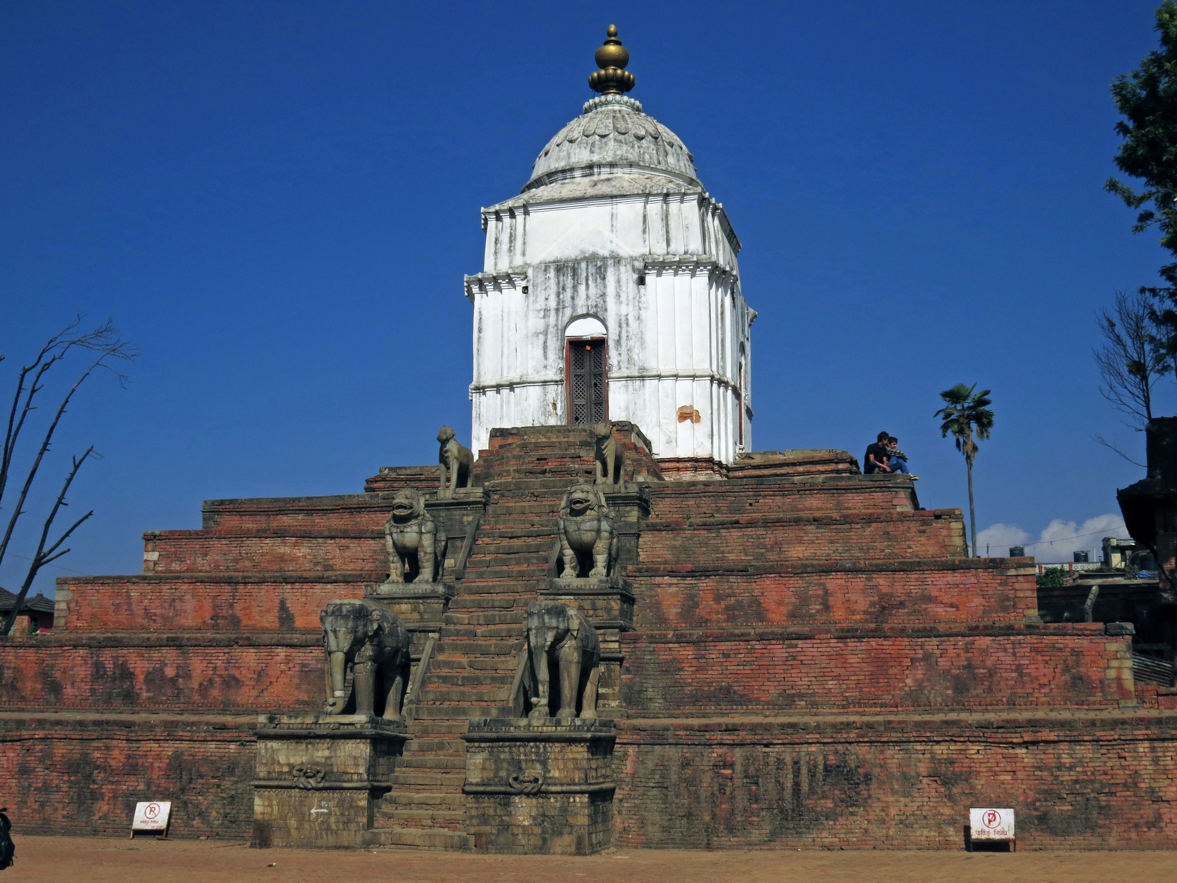 A white temple under a blue sky with stone elephant statues