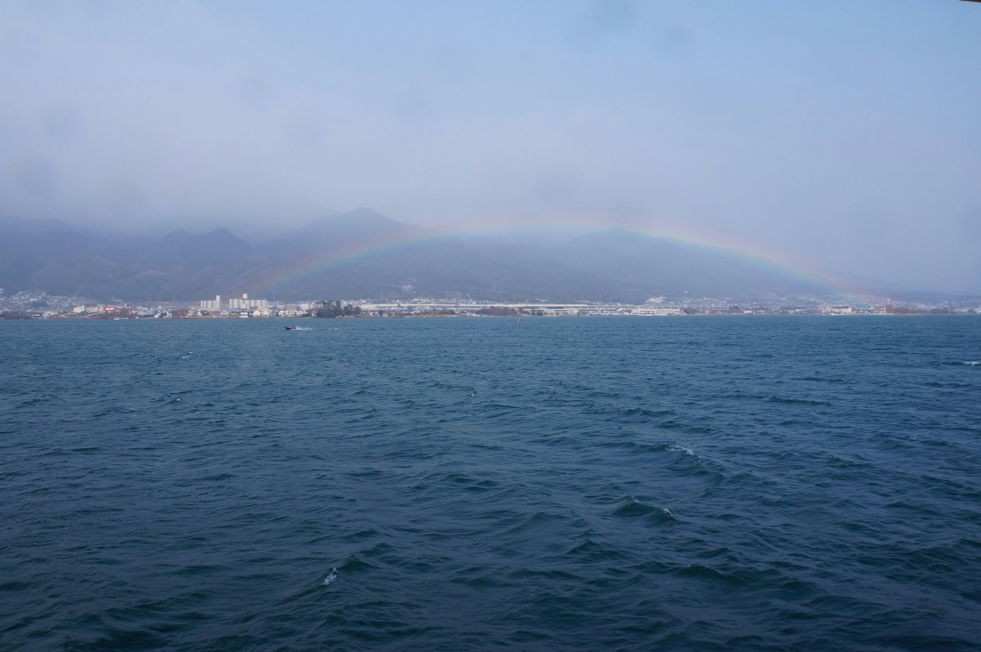 Scenic view of blue ocean with misty mountains in the background