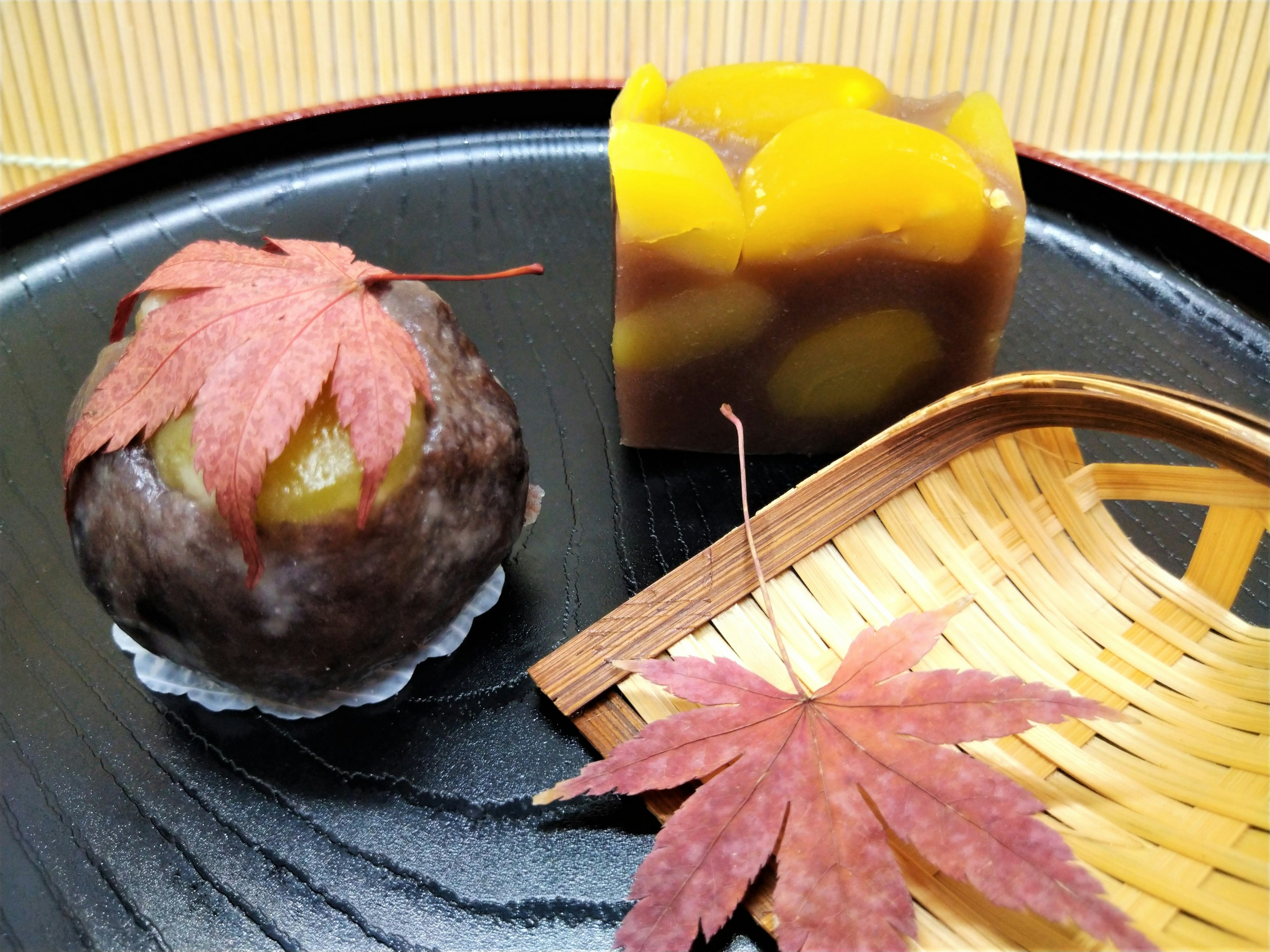 Desserts japonais présentés sur une assiette noire avec des feuilles d'érable