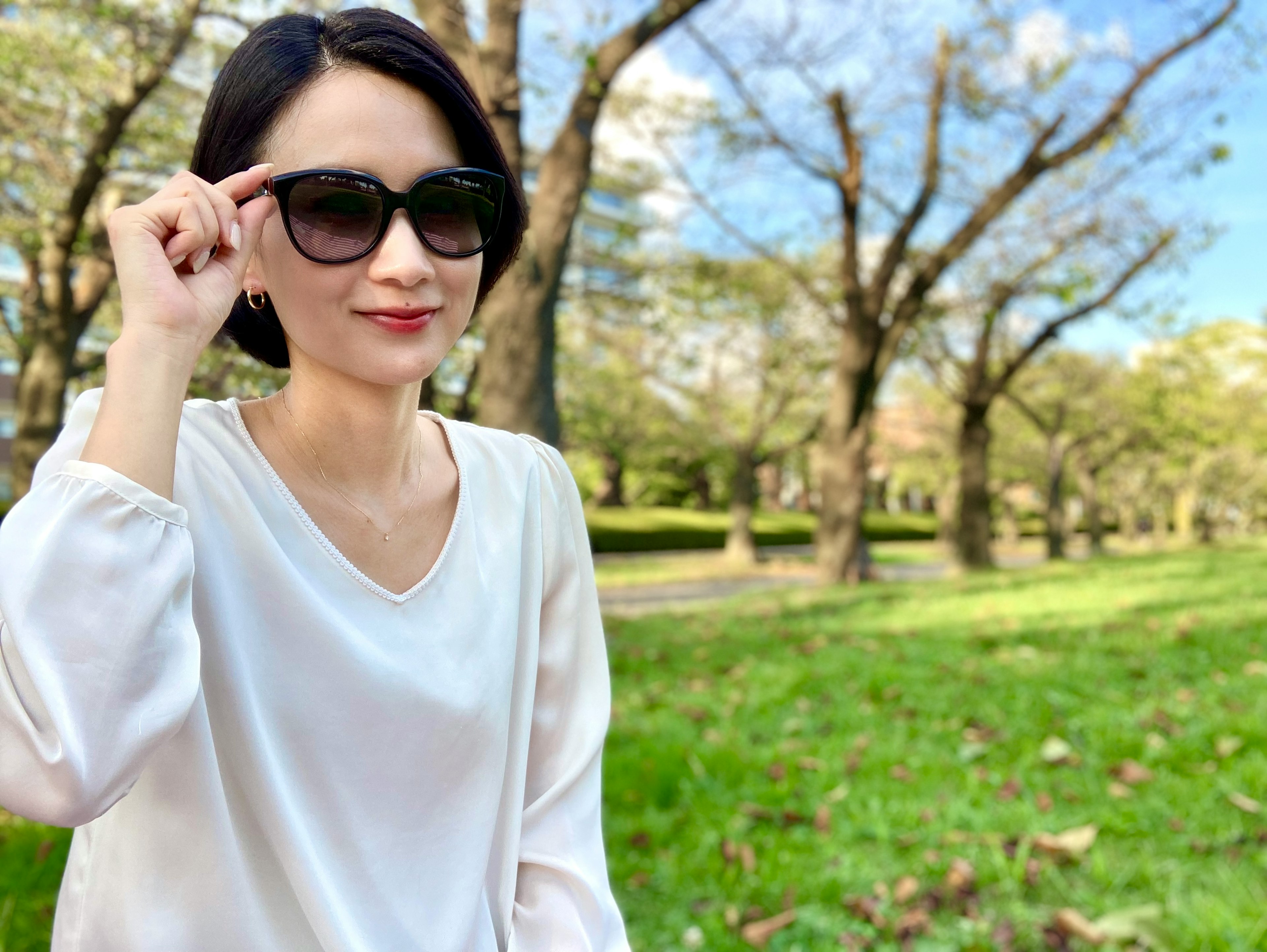 Une femme portant des lunettes de soleil souriant dans un parc