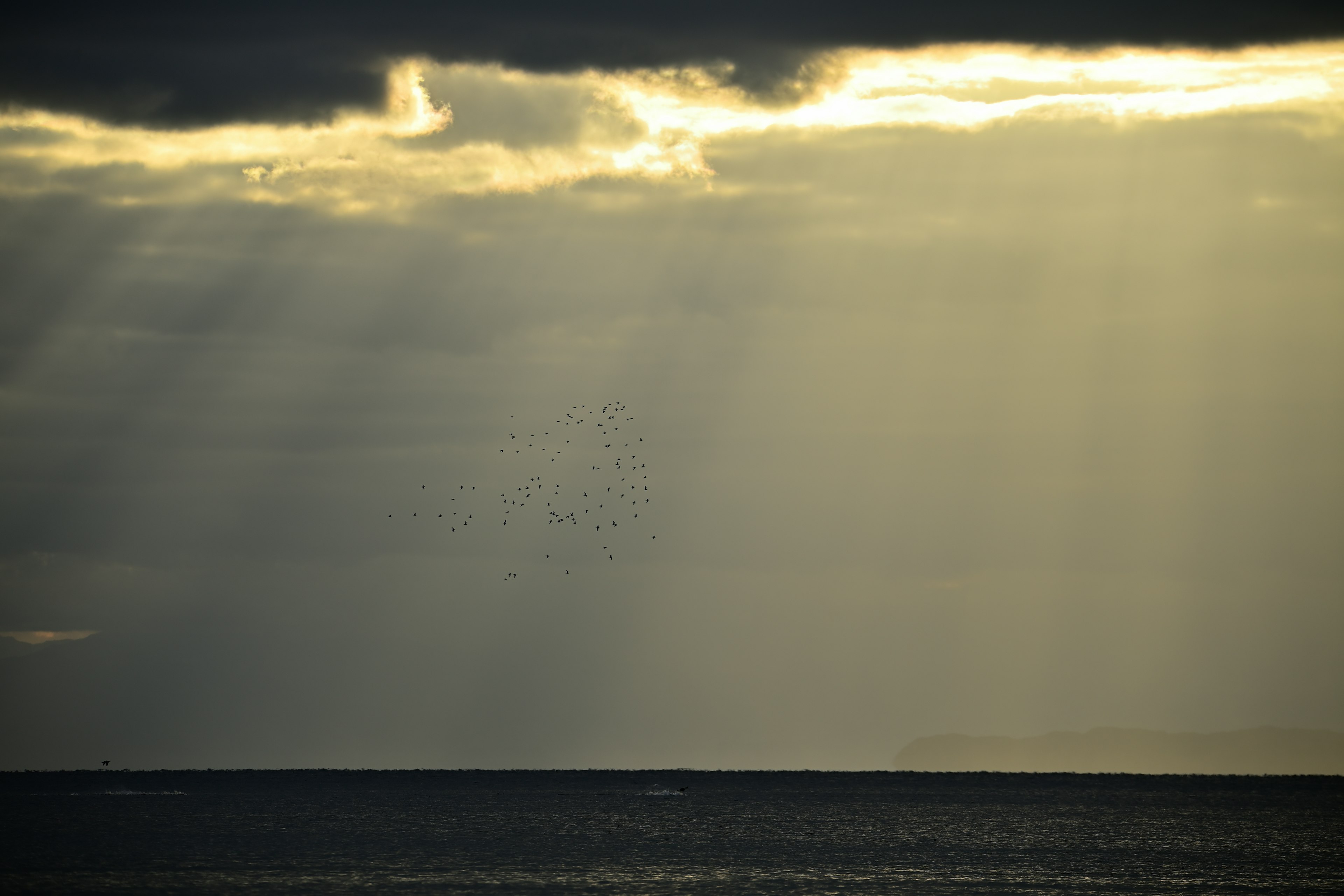 Rays of light breaking through cloudy skies over the ocean