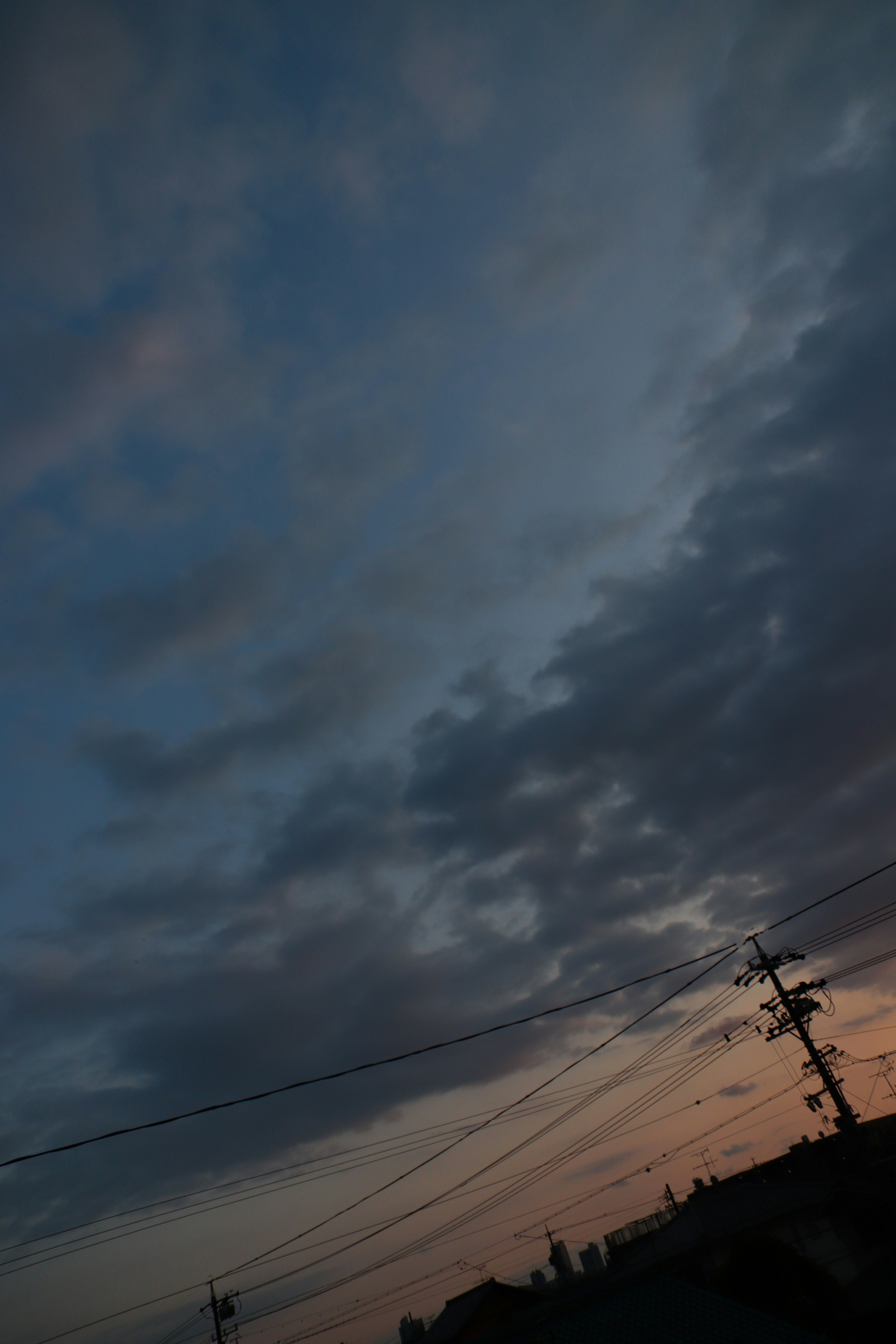 Dämmerungshimmel mit Wolken und Silhouette eines Strommasts