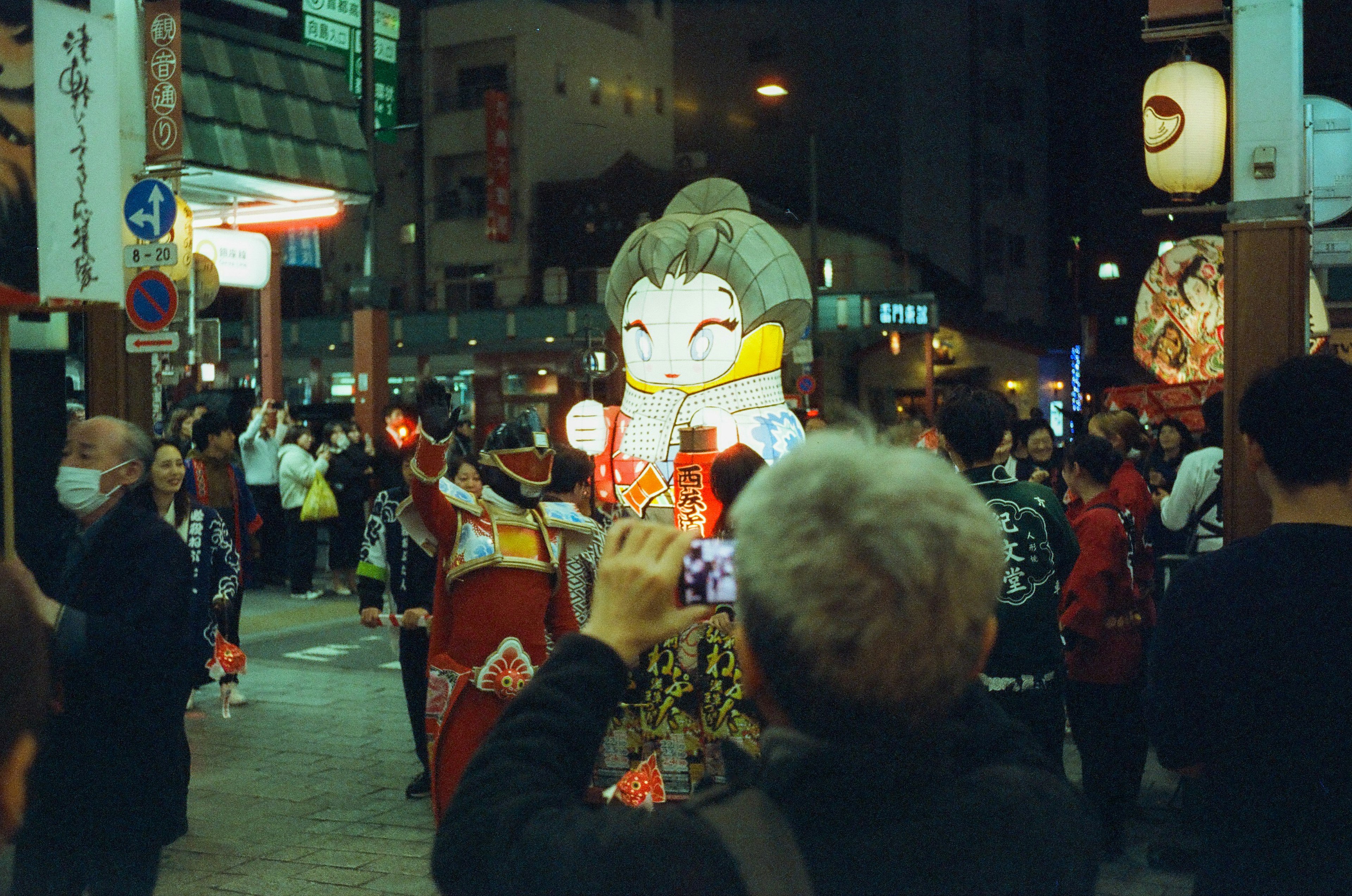 Crowd gathered at night festival featuring a large traditional doll