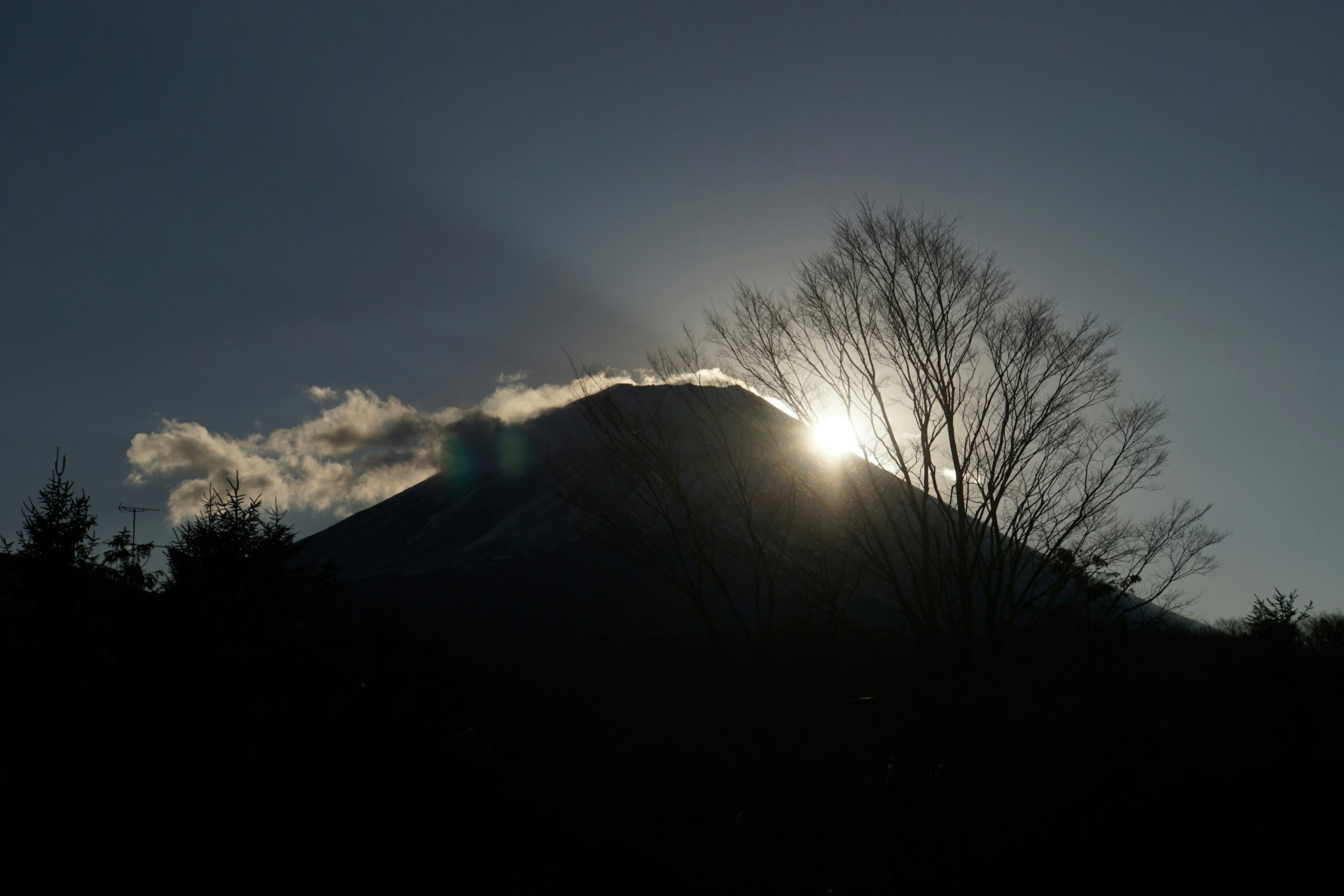 山のシルエットが夕日を背景に浮かび上がる景色