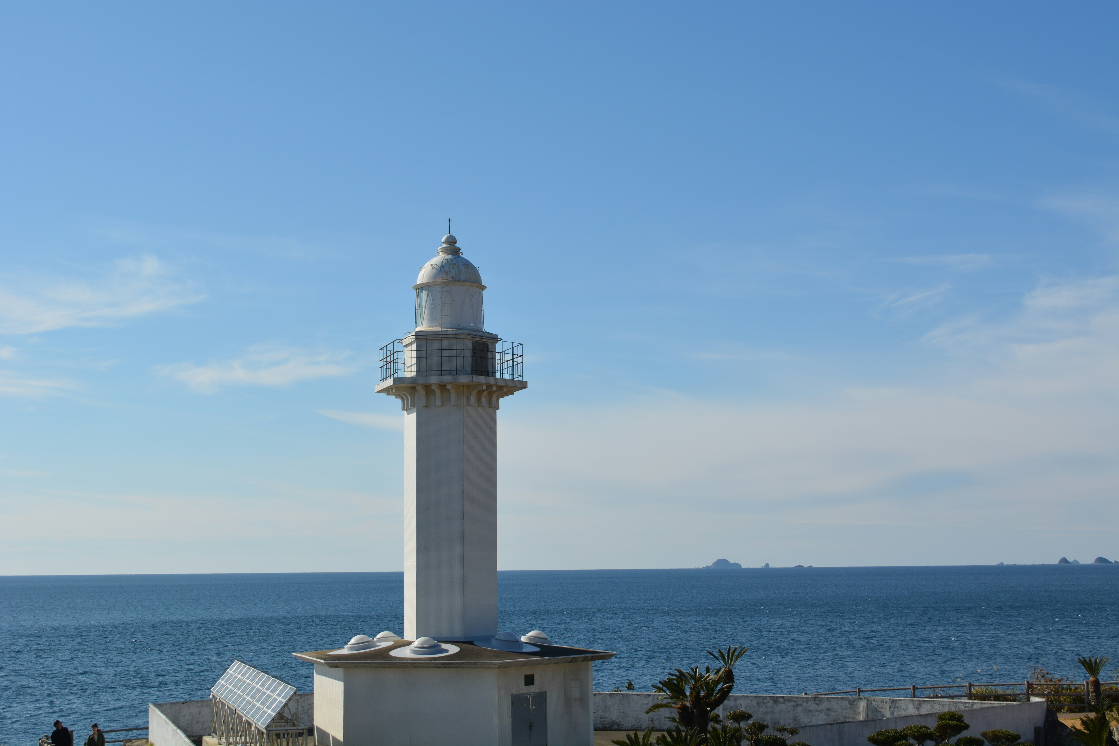 A white lighthouse stands against a blue ocean