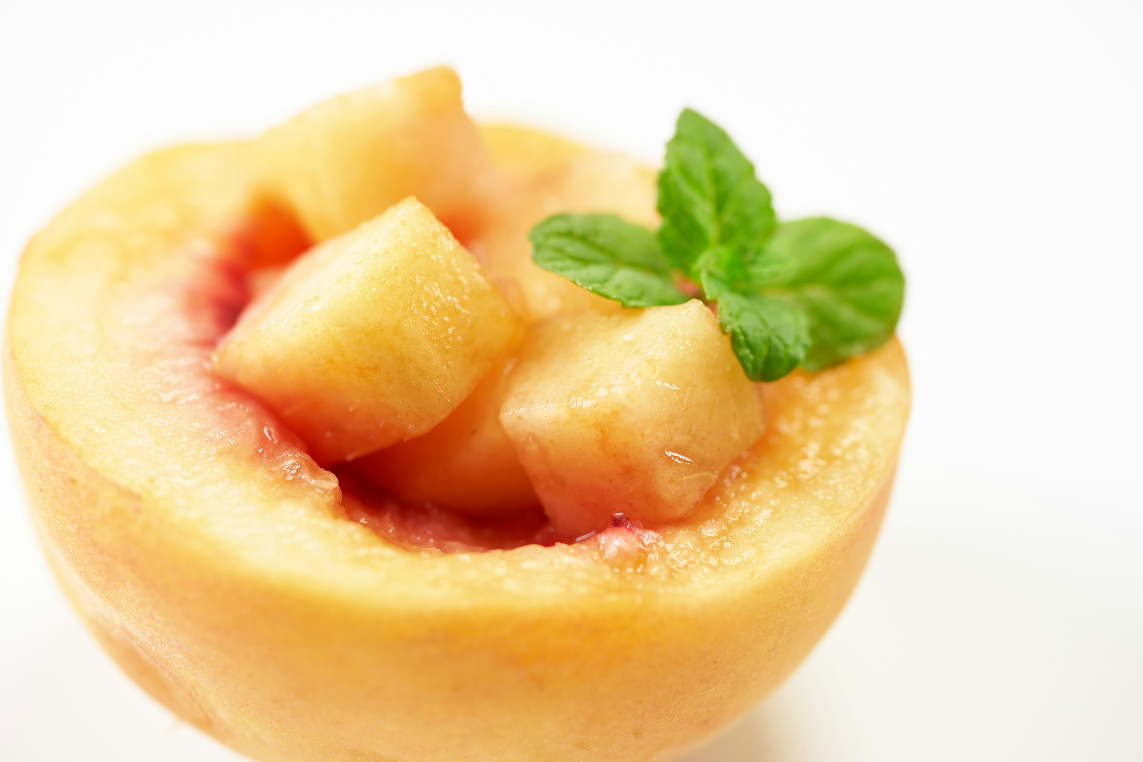 Fresh peach half with diced flesh and mint garnish