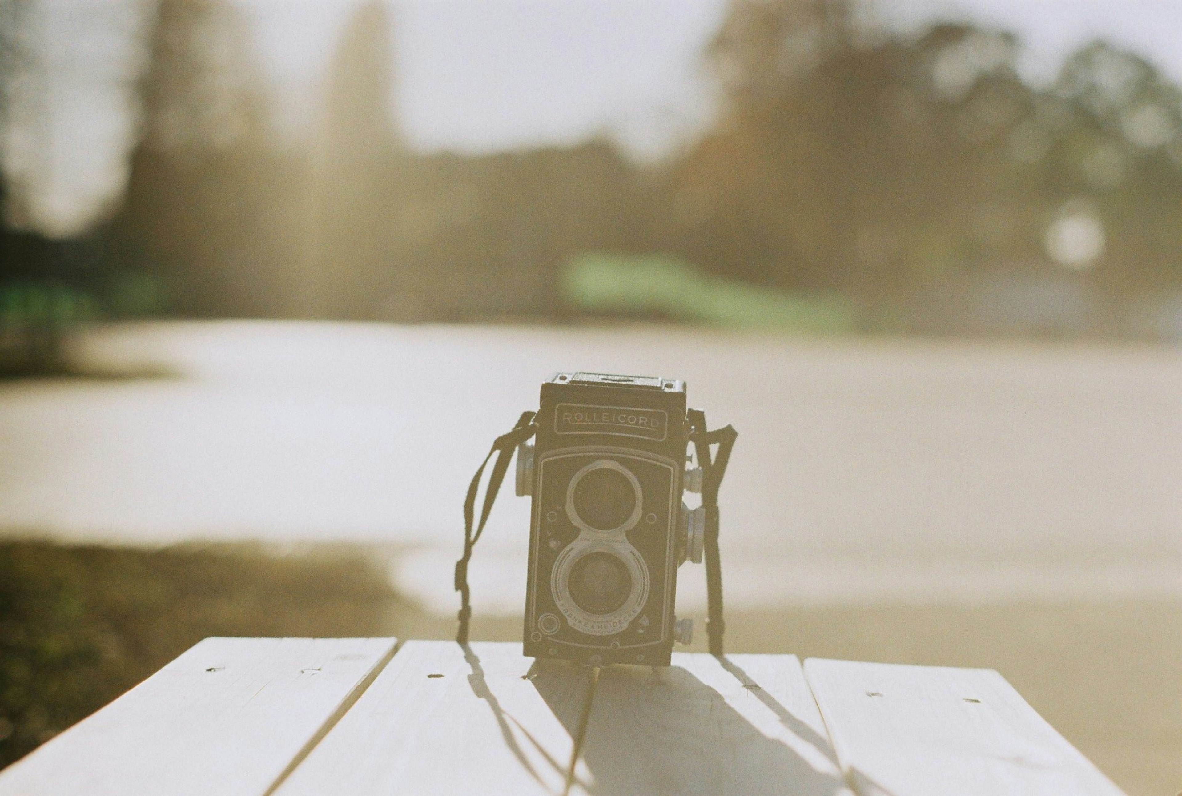 A retro twin-lens reflex camera placed on a table in soft sunlight