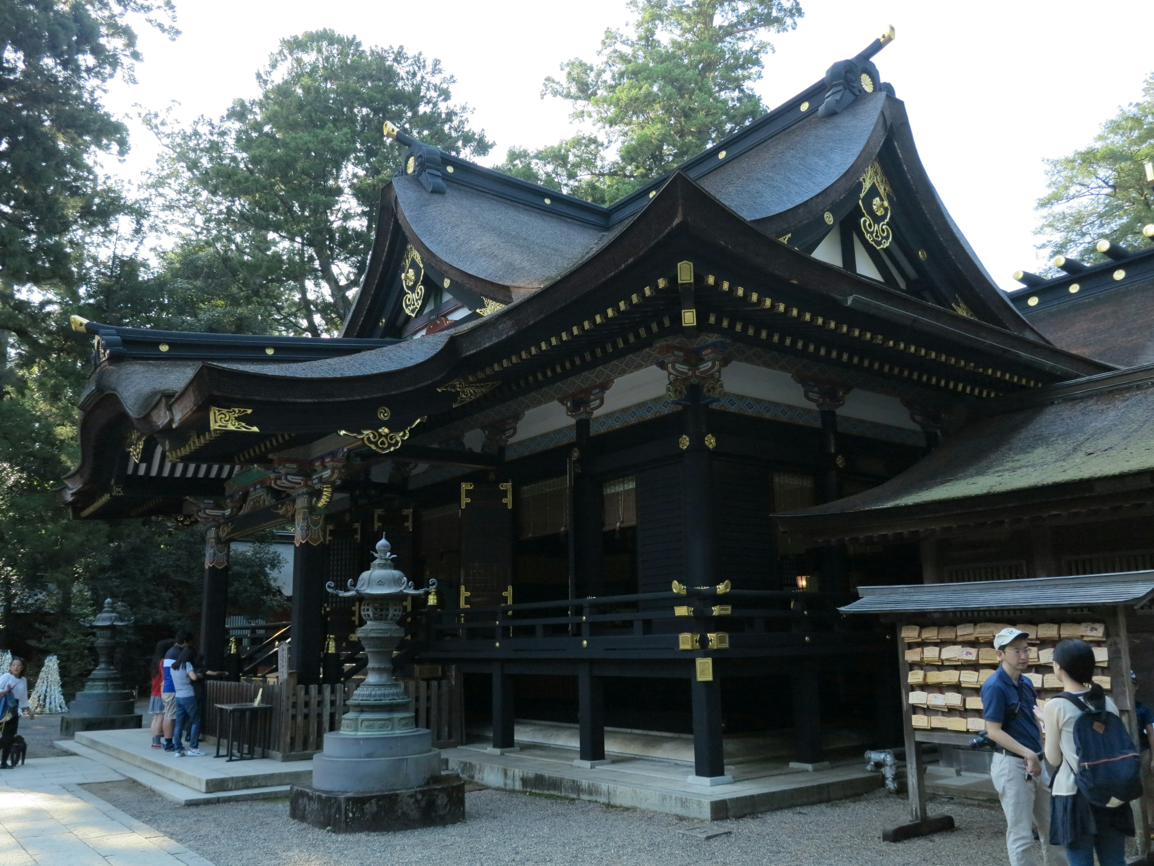 黑色神社建筑装饰着金色装饰，周围是绿色树木