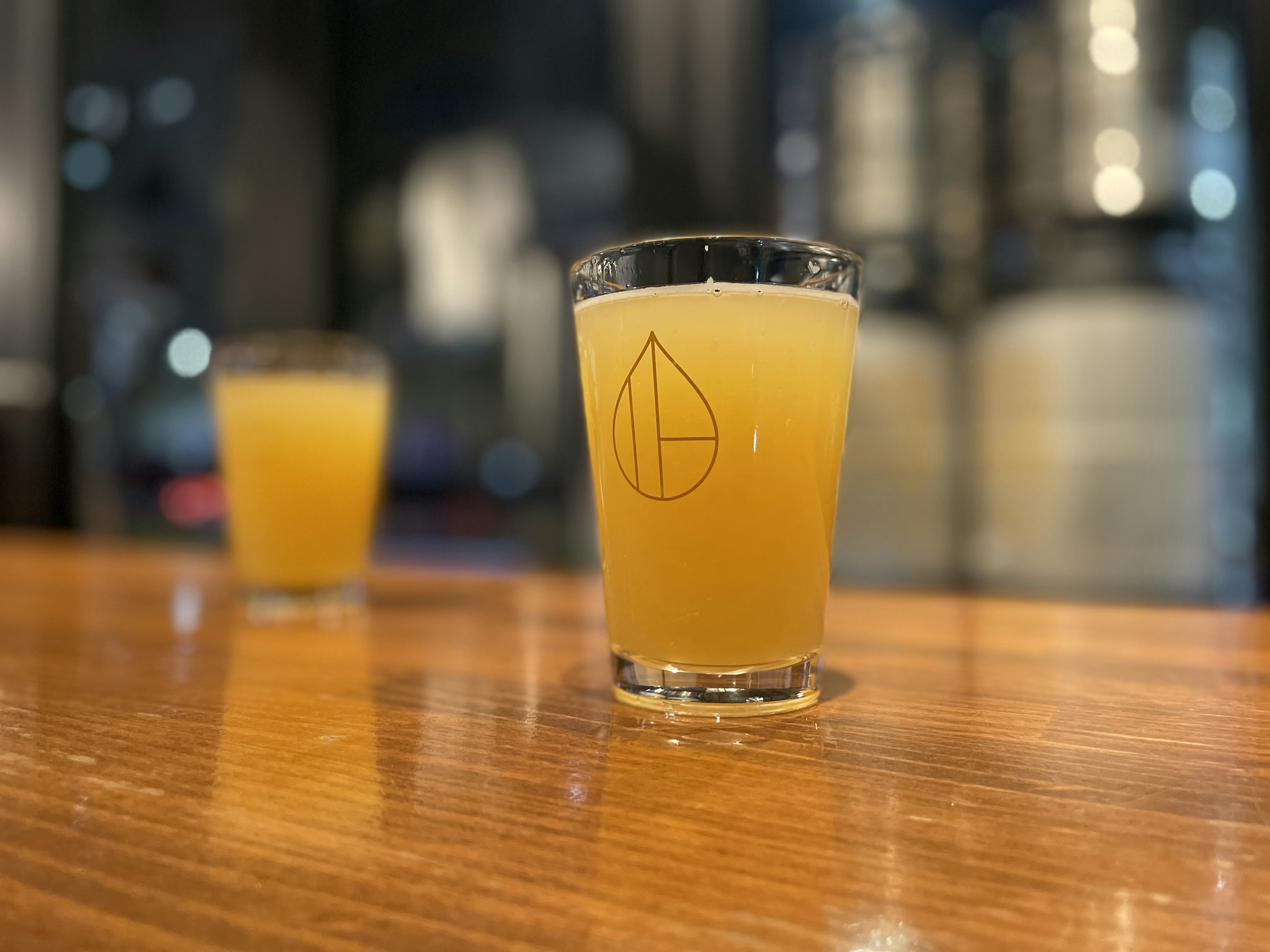 A clear glass filled with yellow beverage on a wooden table