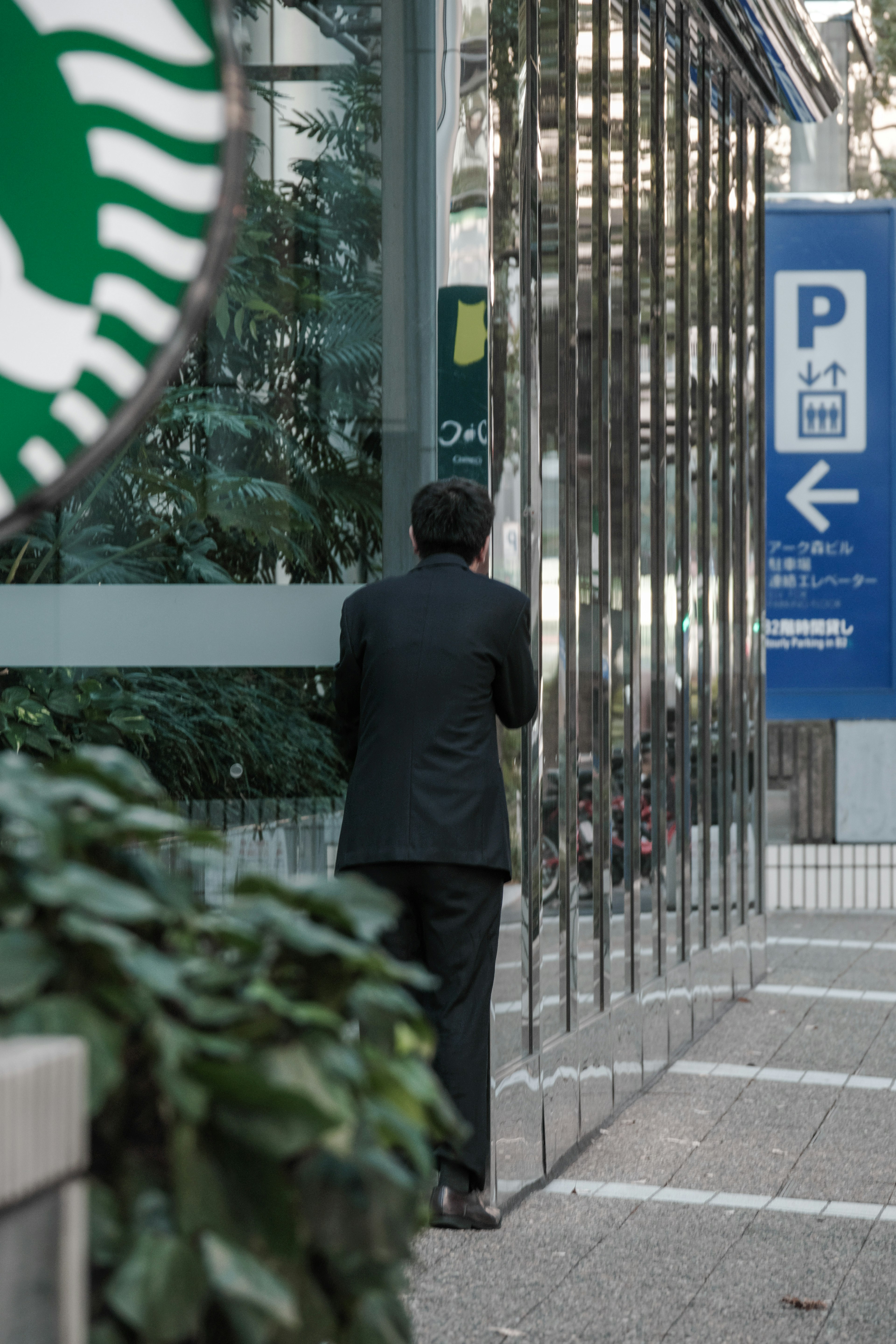 Ein Mann im Anzug steht vor einer Glaswand mit einem Starbucks-Logo auf der linken Seite