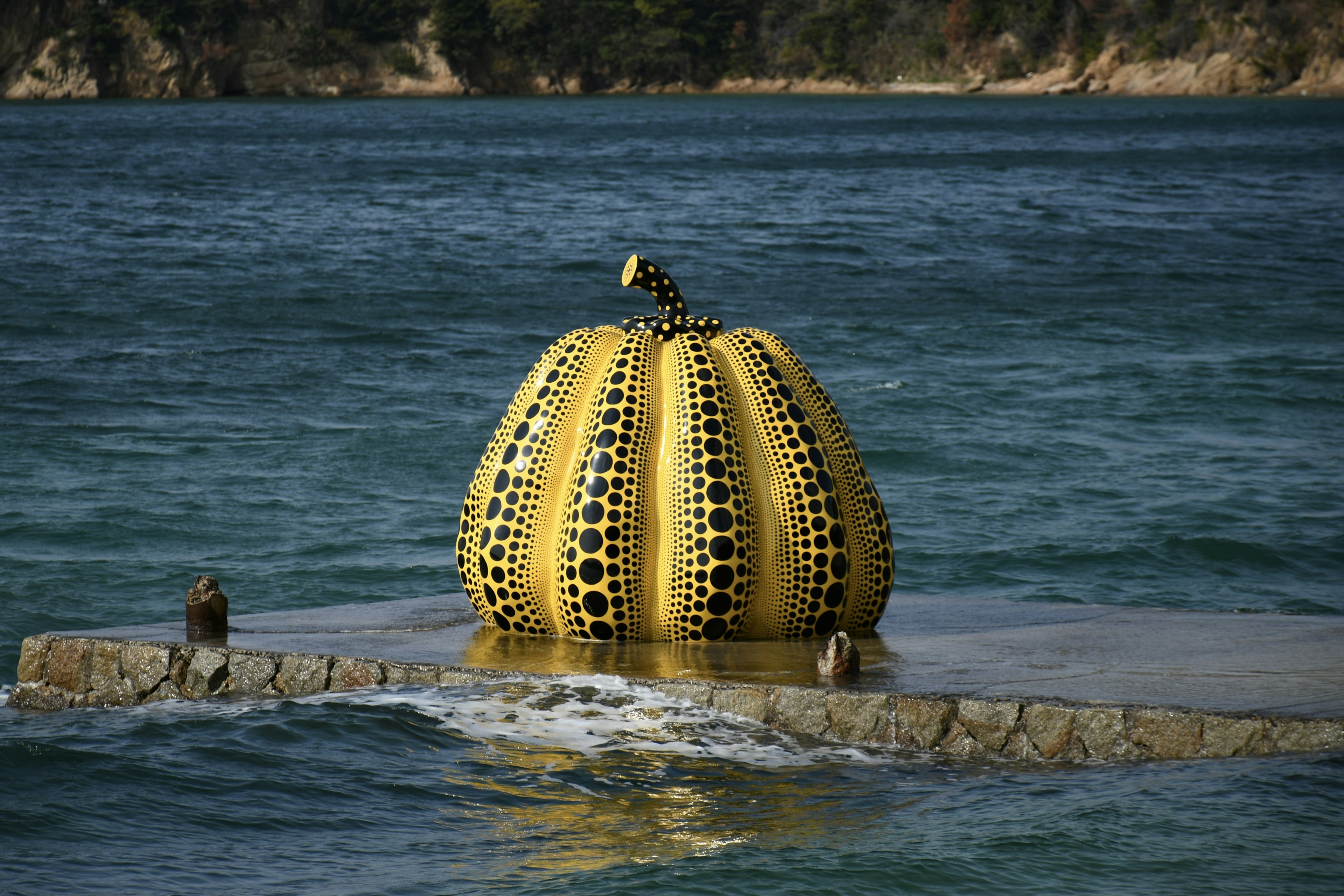 Escultura de calabaza amarilla flotando sobre el agua