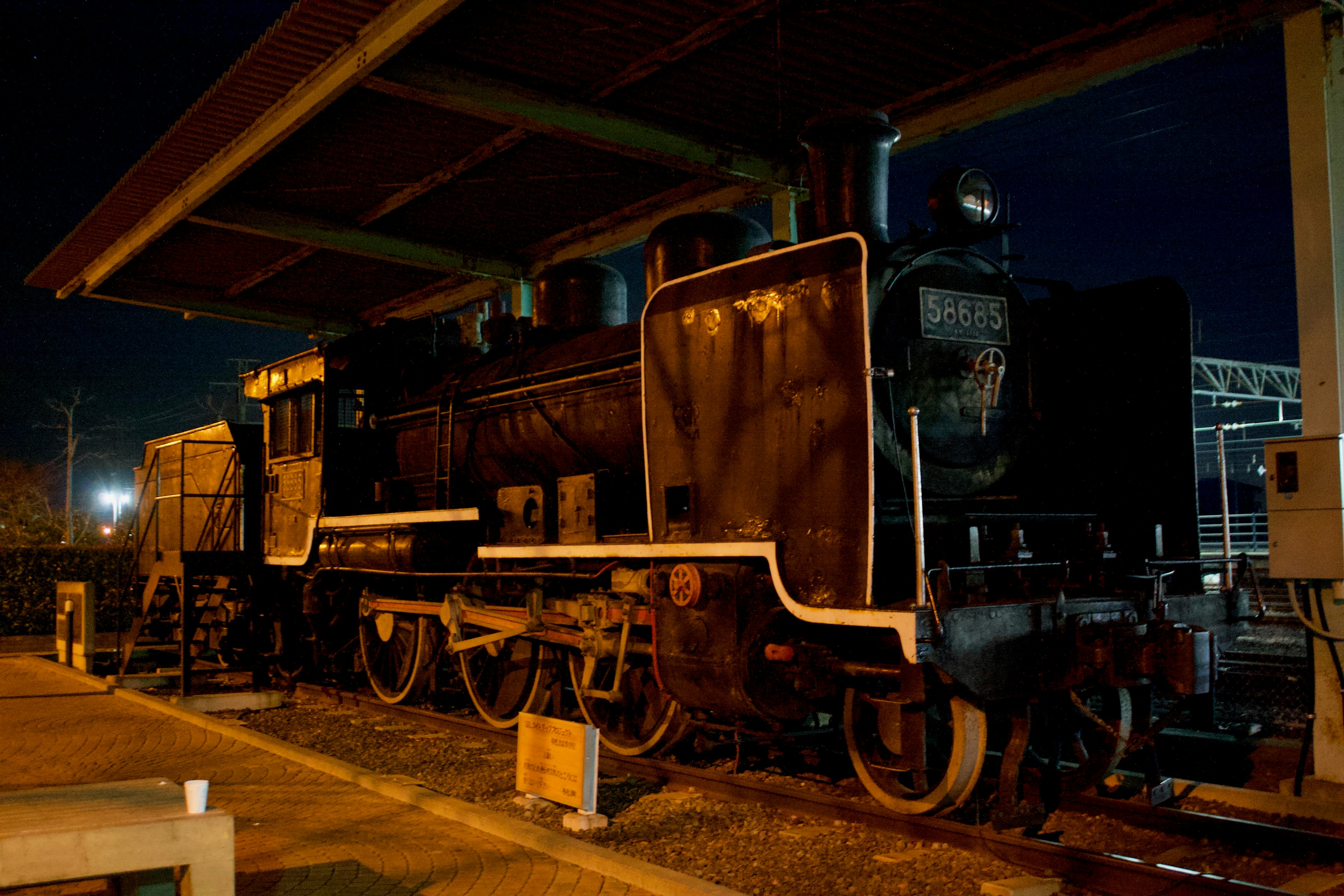 Image of an old steam locomotive under a shelter at night