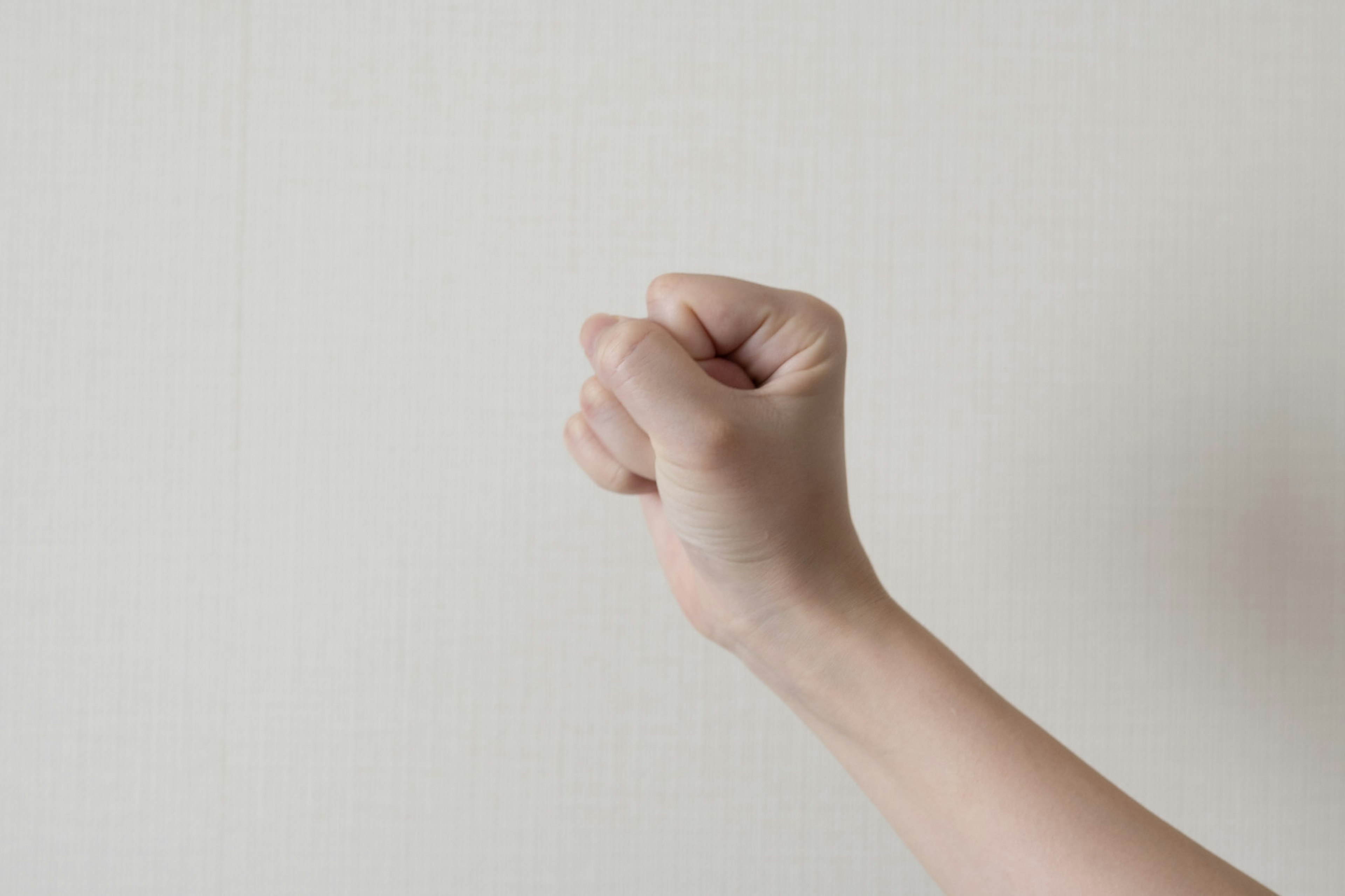 A clenched fist against a plain white wall