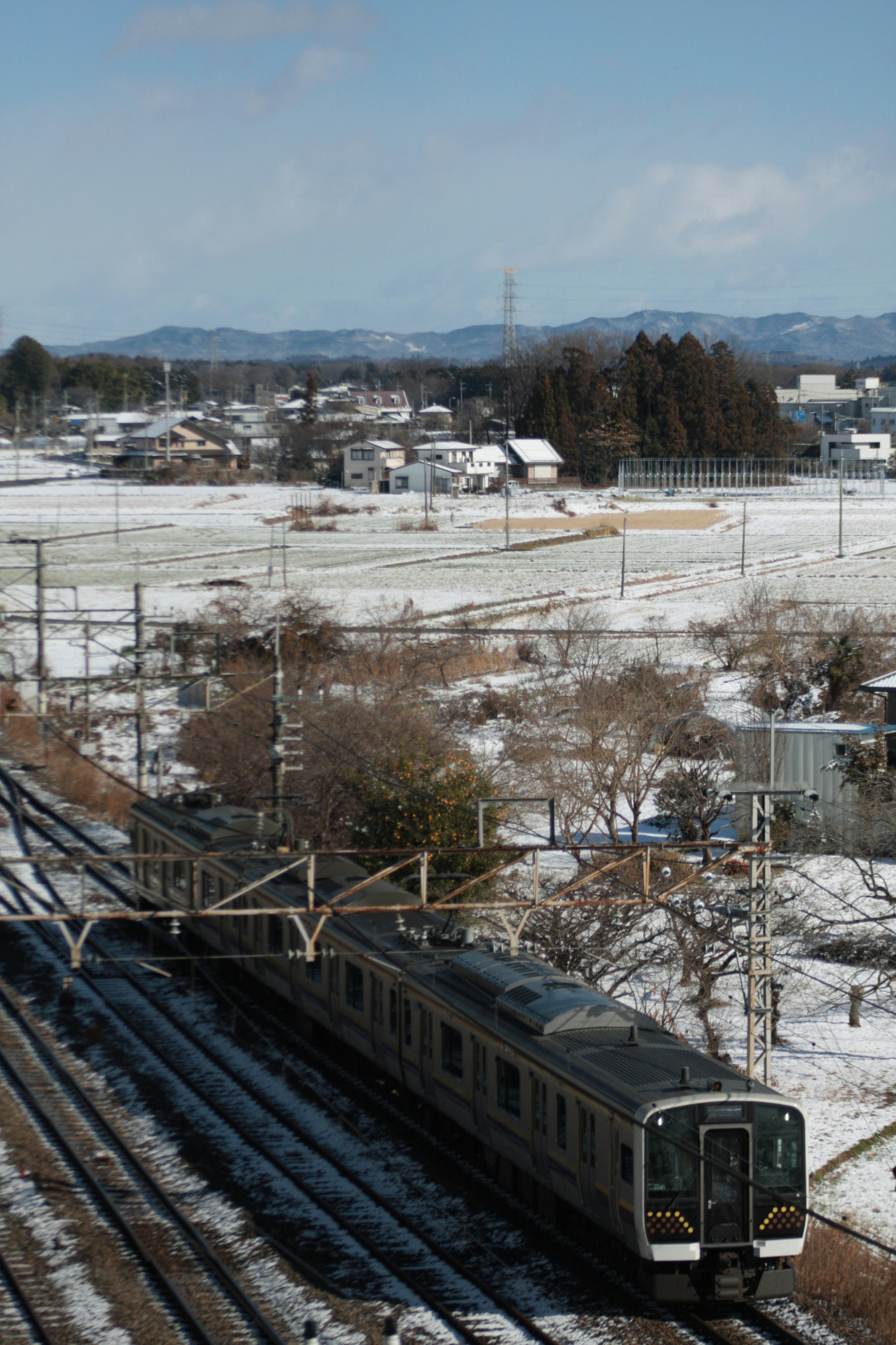 รถไฟที่วิ่งผ่านภูมิทัศน์ที่มีหิมะและทุ่งนาต่างๆ