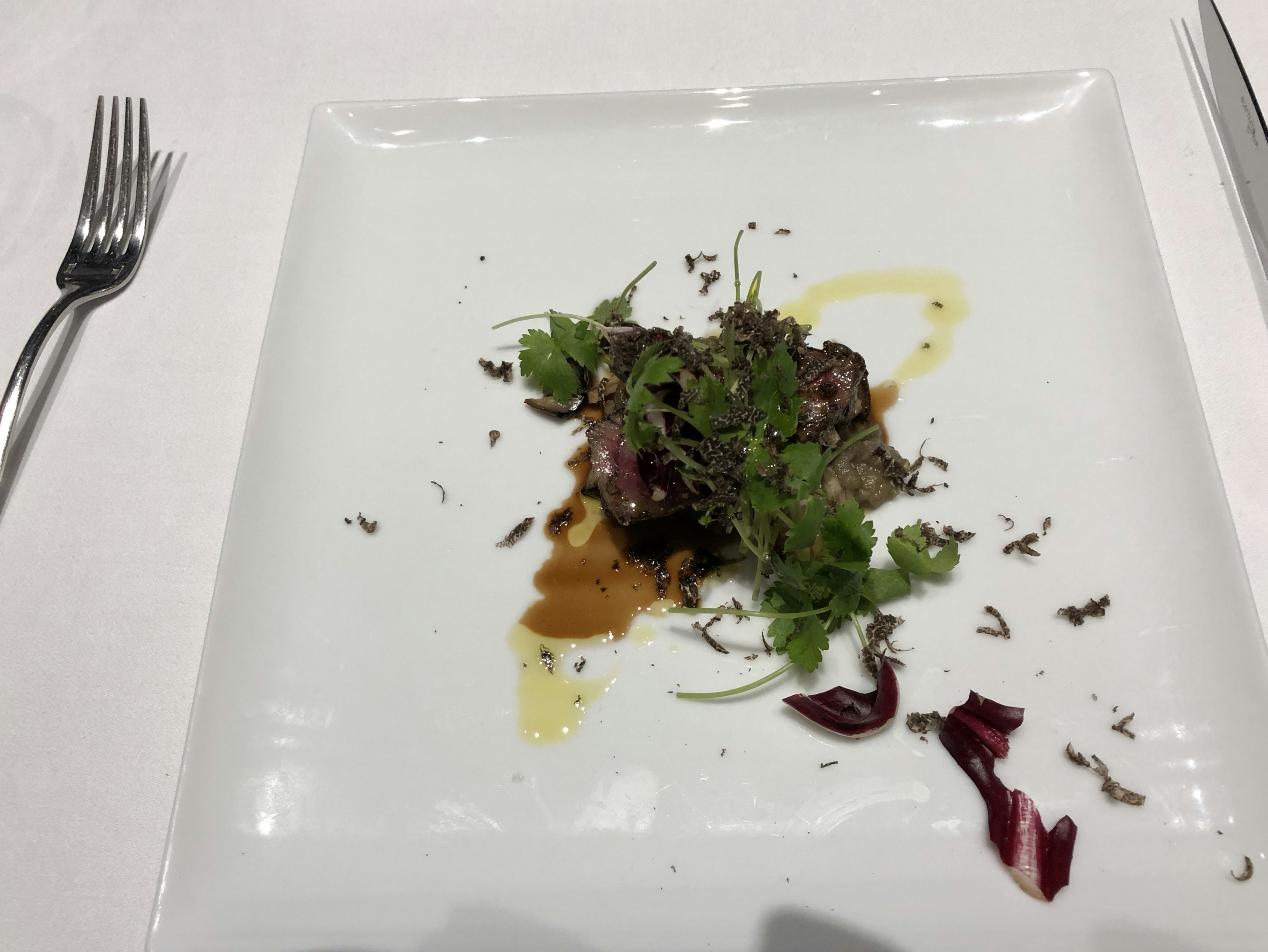 Un plat sur une assiette blanche avec de la viande garnie de légumes verts et de sauce