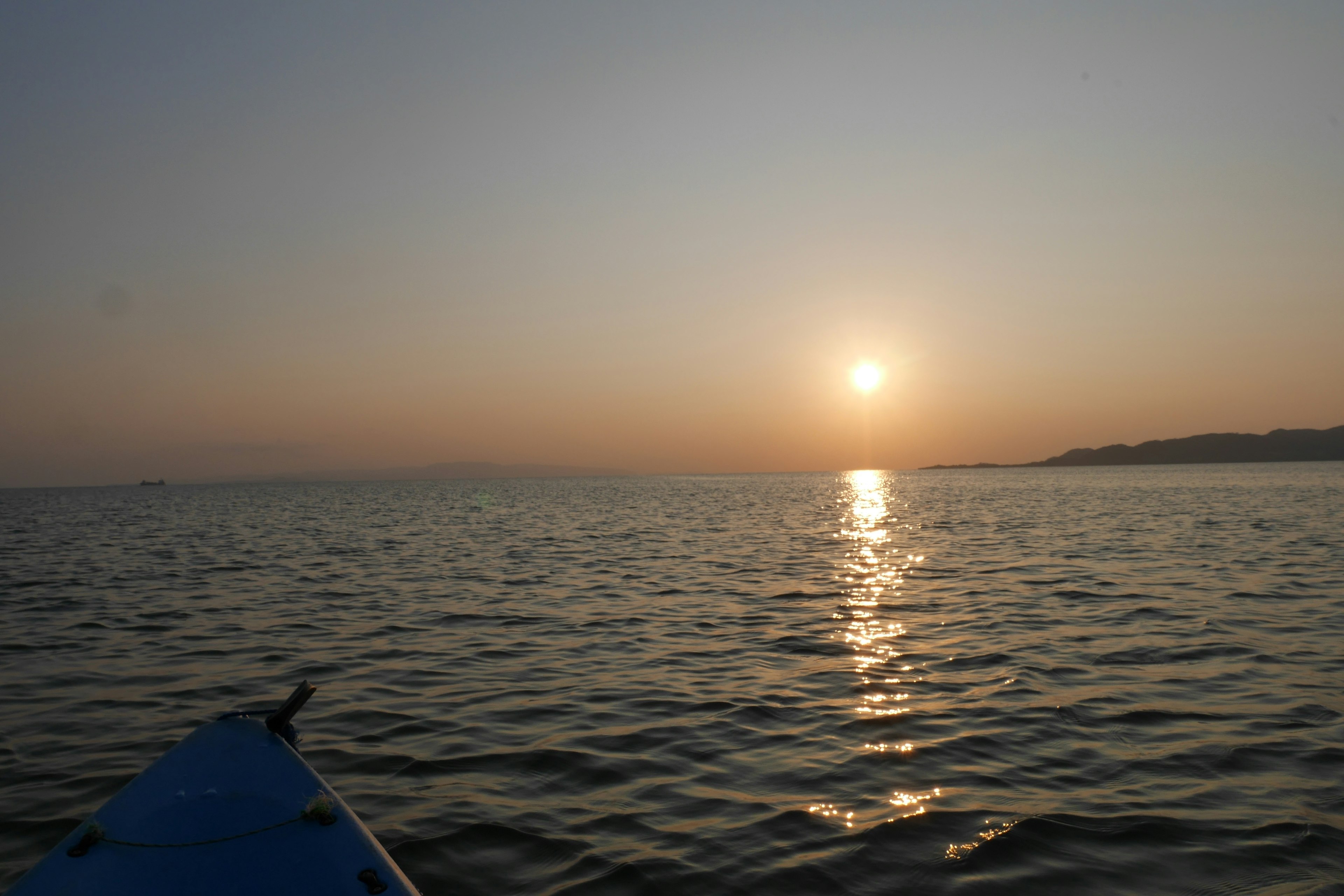 海に浮かぶカヤックからの夕日と穏やかな水面