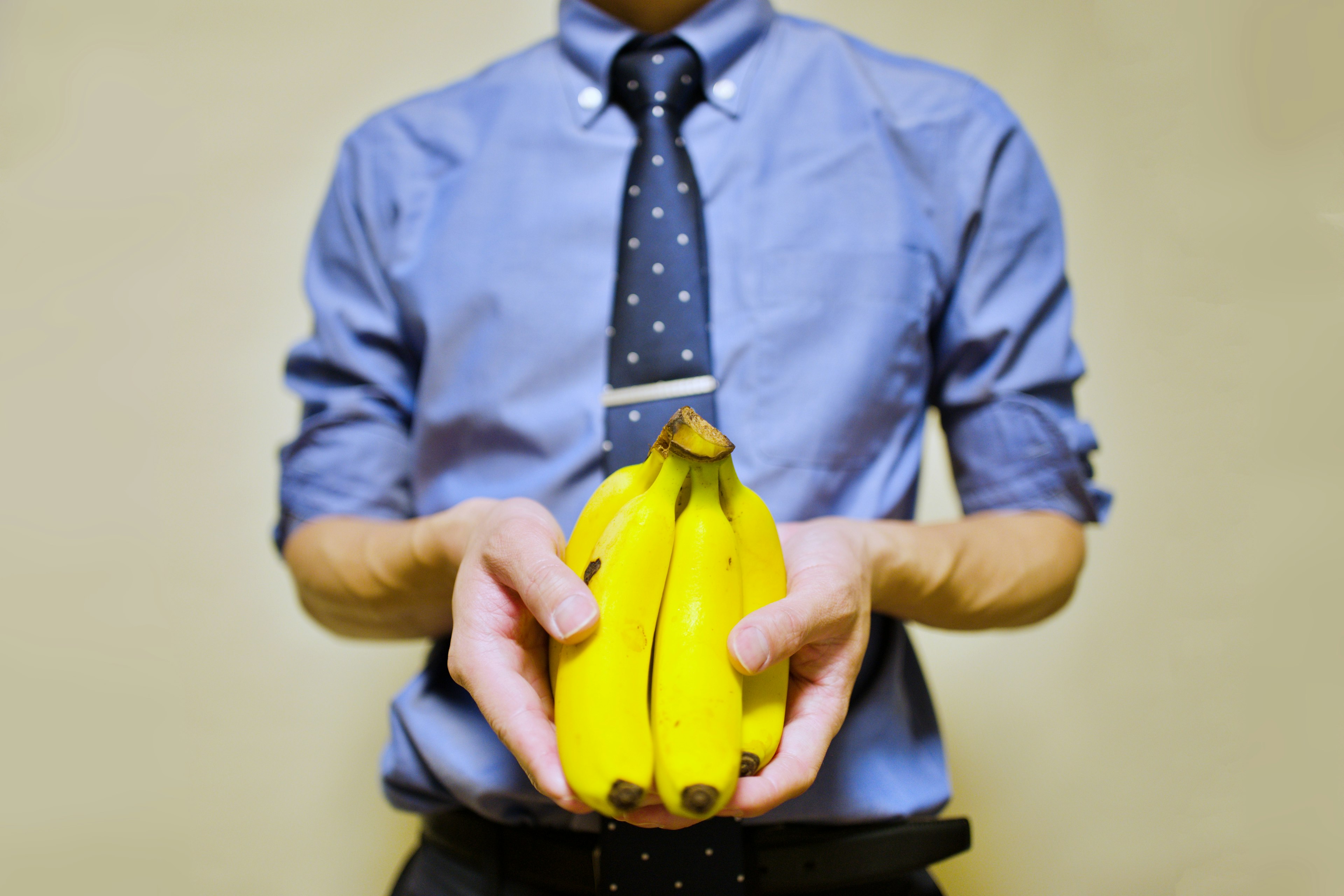 Mann mit Krawatte hält Bananen