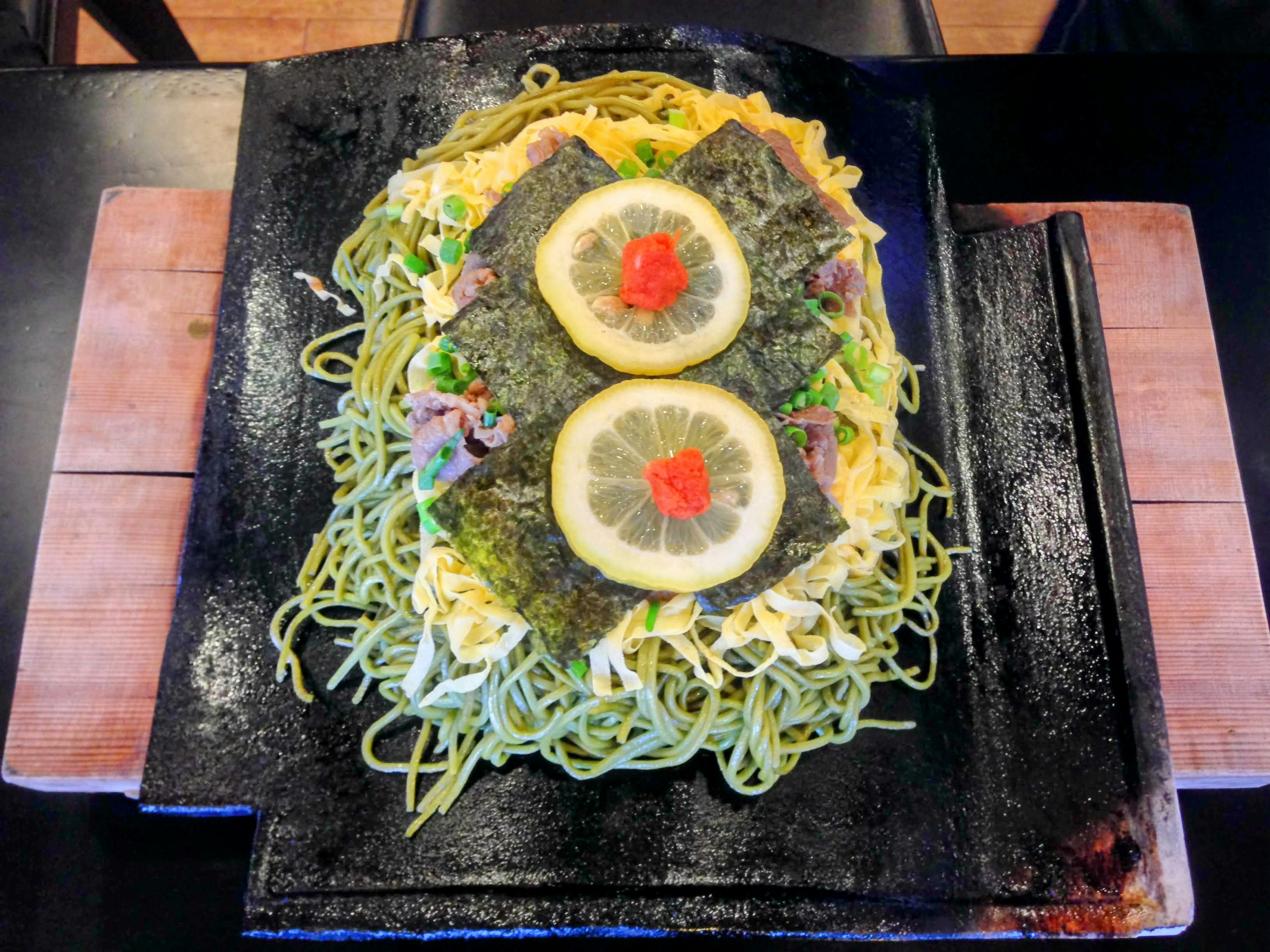 Stir-fried noodles topped with lemon slices and seaweed