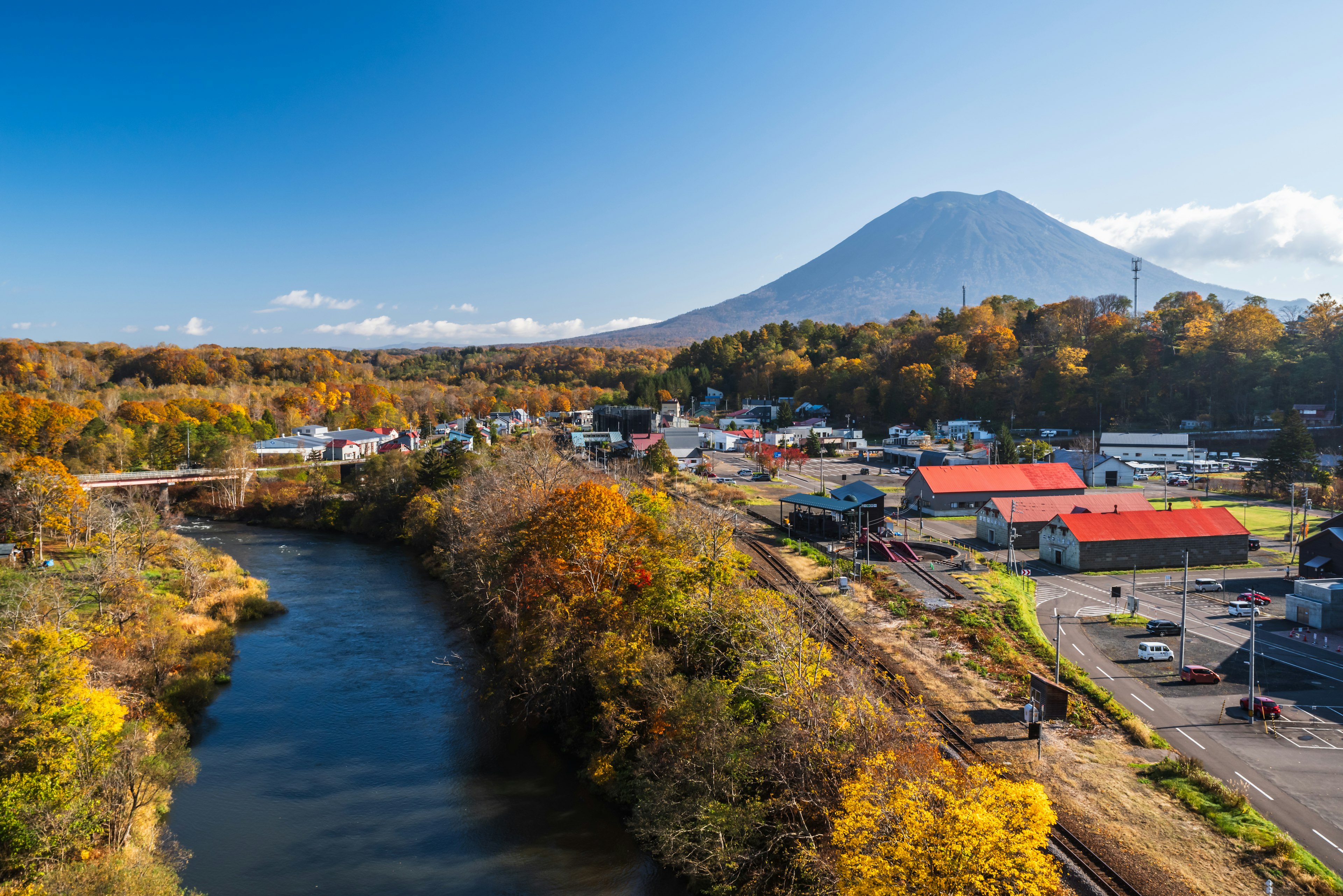 Un villaggio pittoresco con fogliame autunnale vicino a un fiume e una montagna