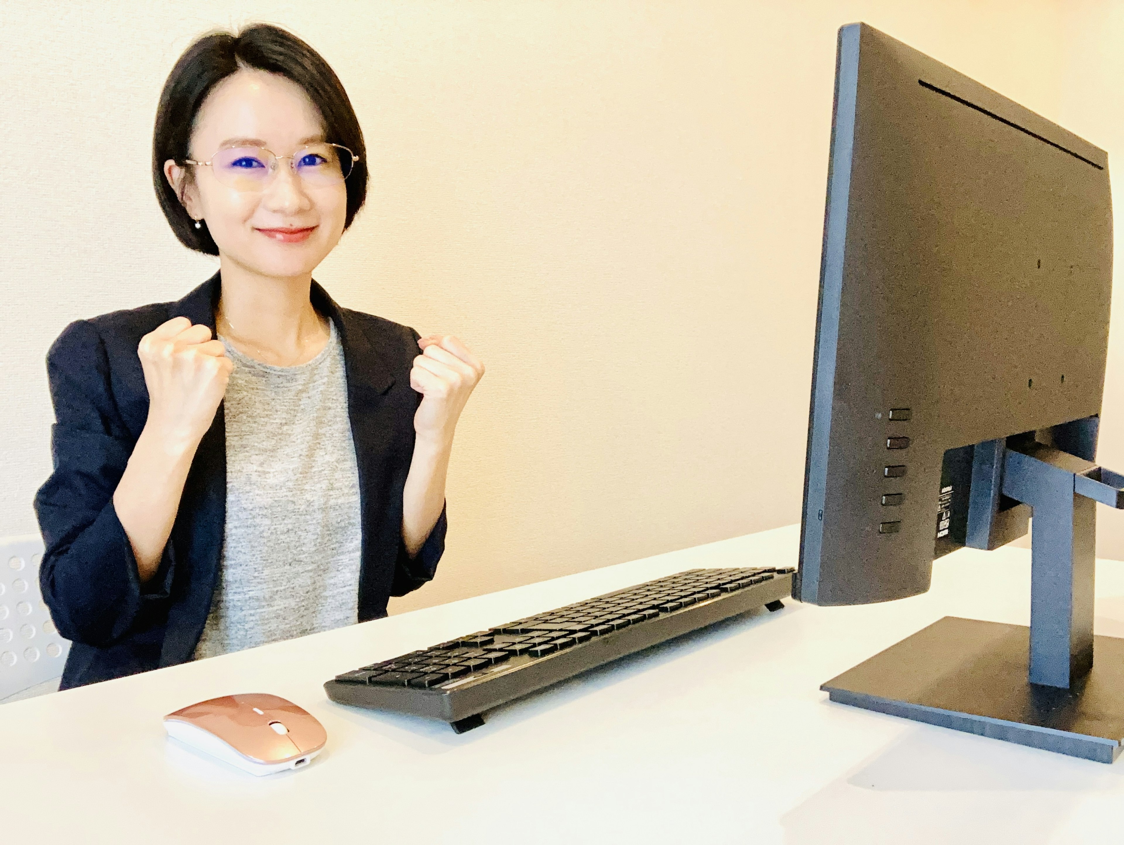 Mujer sonriente sentada en un escritorio frente a una computadora