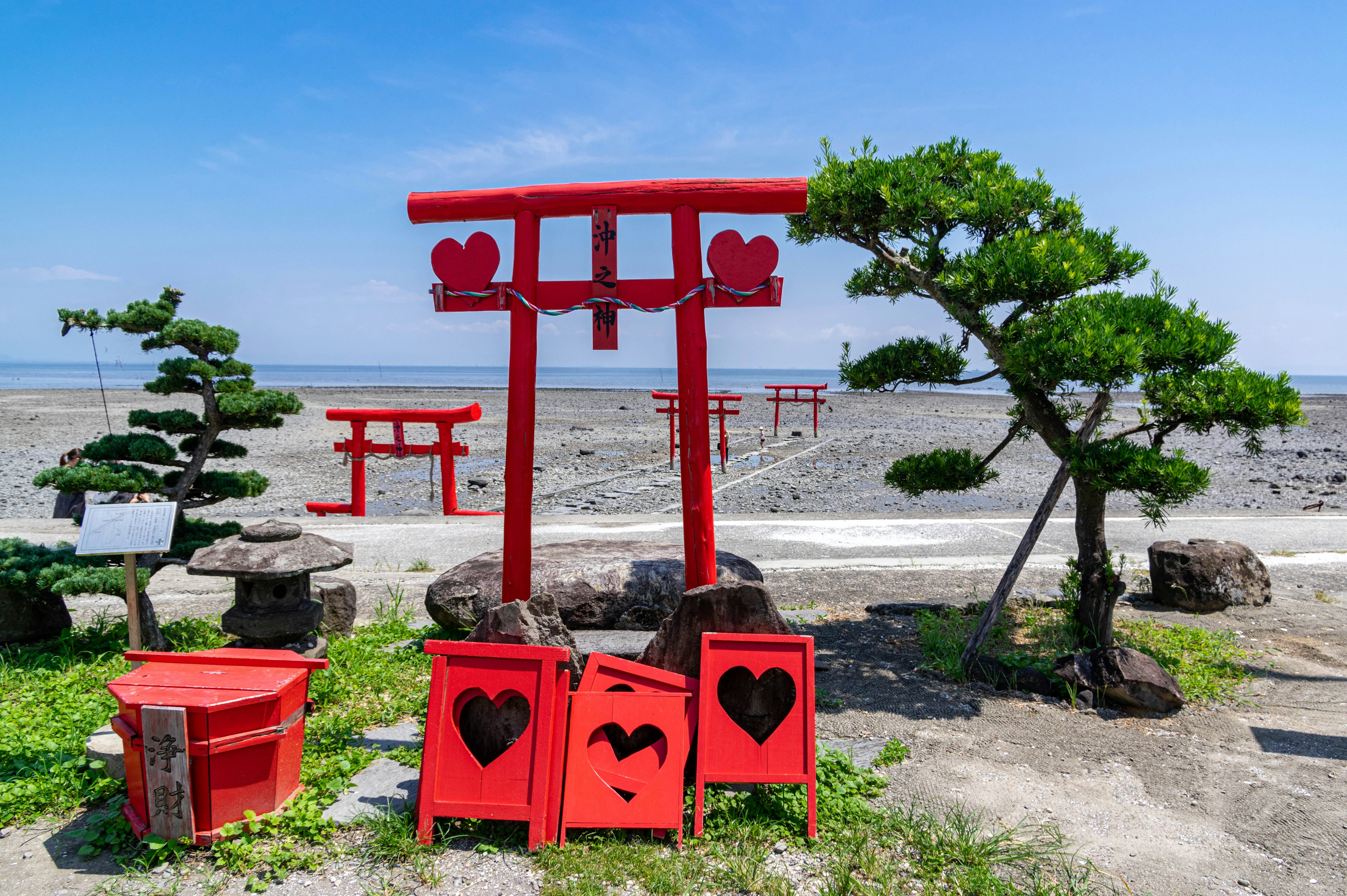 Scenic coastal view featuring a red torii gate and heart-themed signs