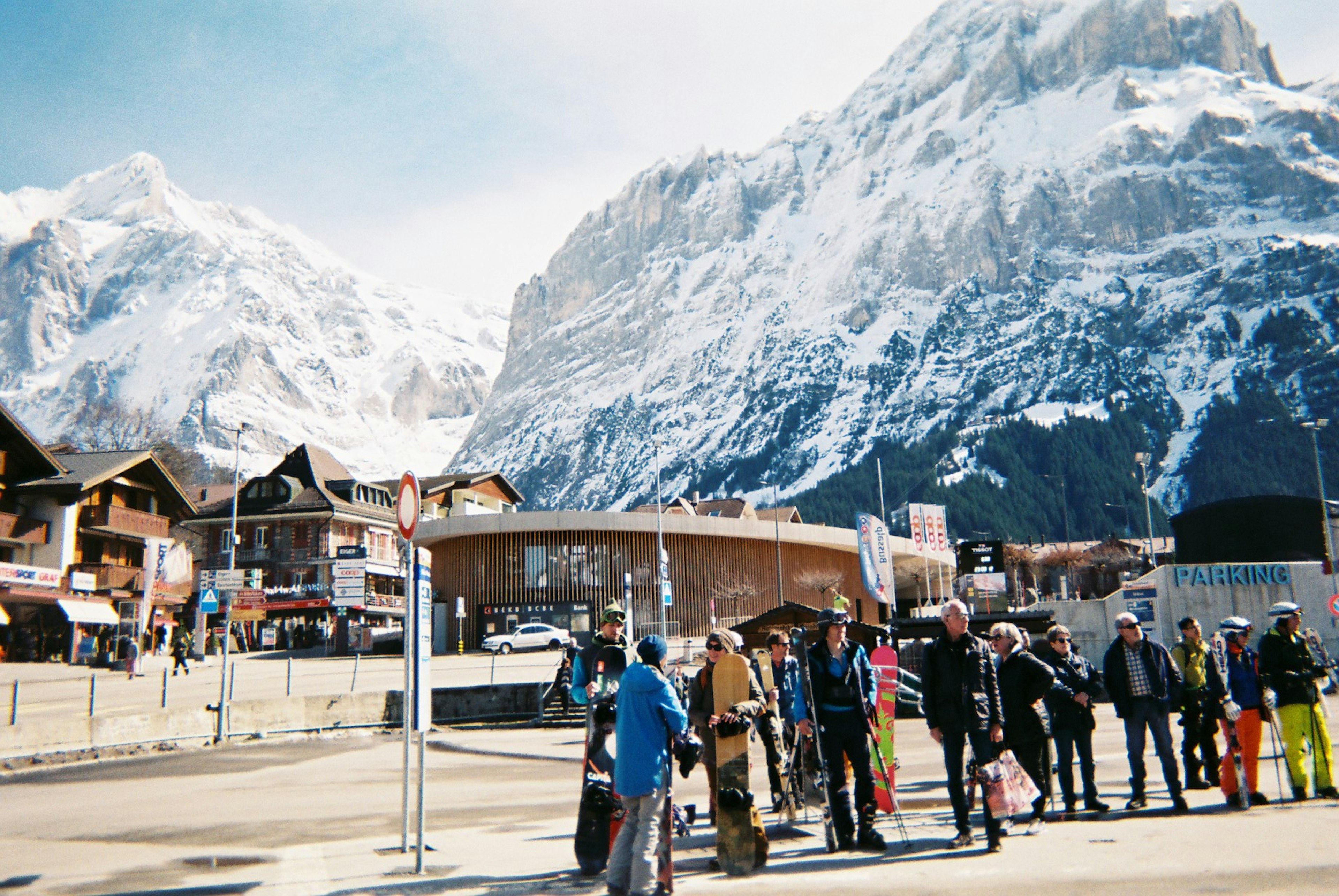 スイスの山々を背景にしたスキーリゾートの風景に人々が並んでいる