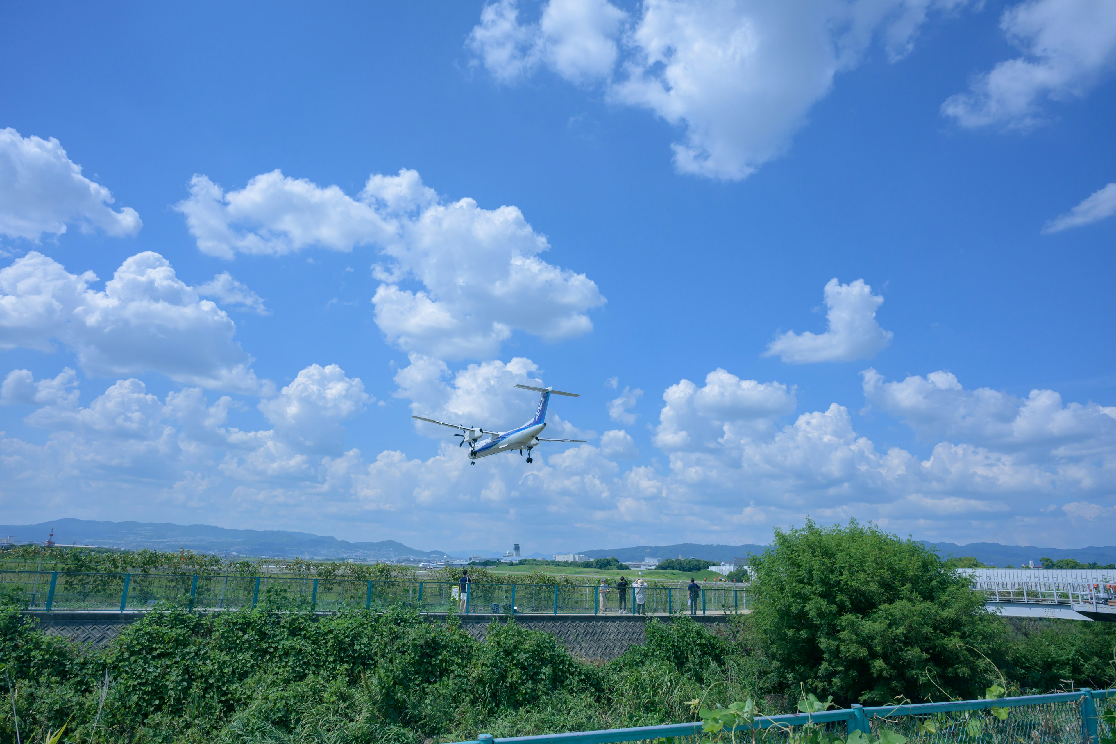 青空と白い雲の下を飛ぶヘリコプターの画像