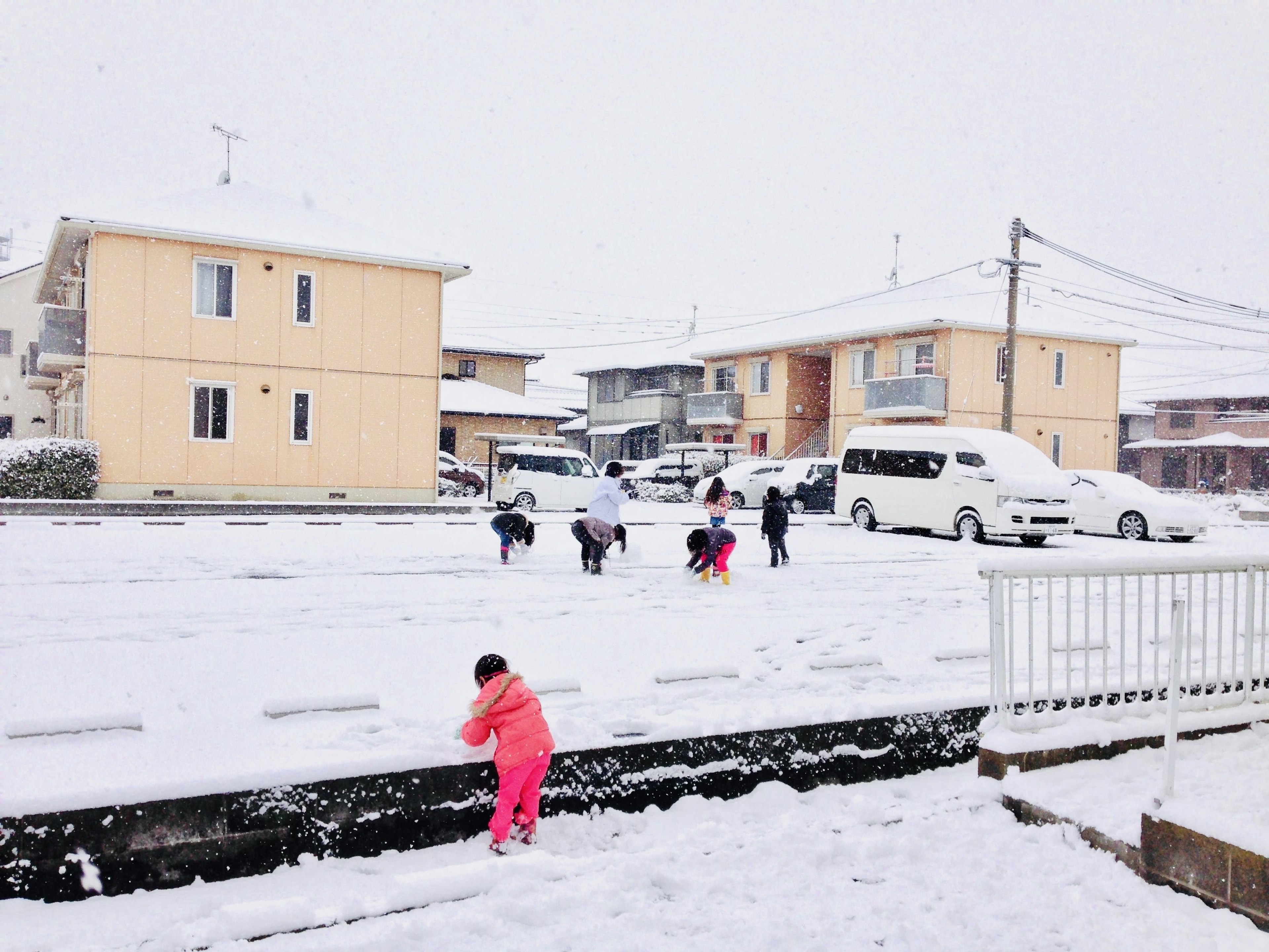 Kinder spielen im Schnee mit Wohngebäuden im Hintergrund