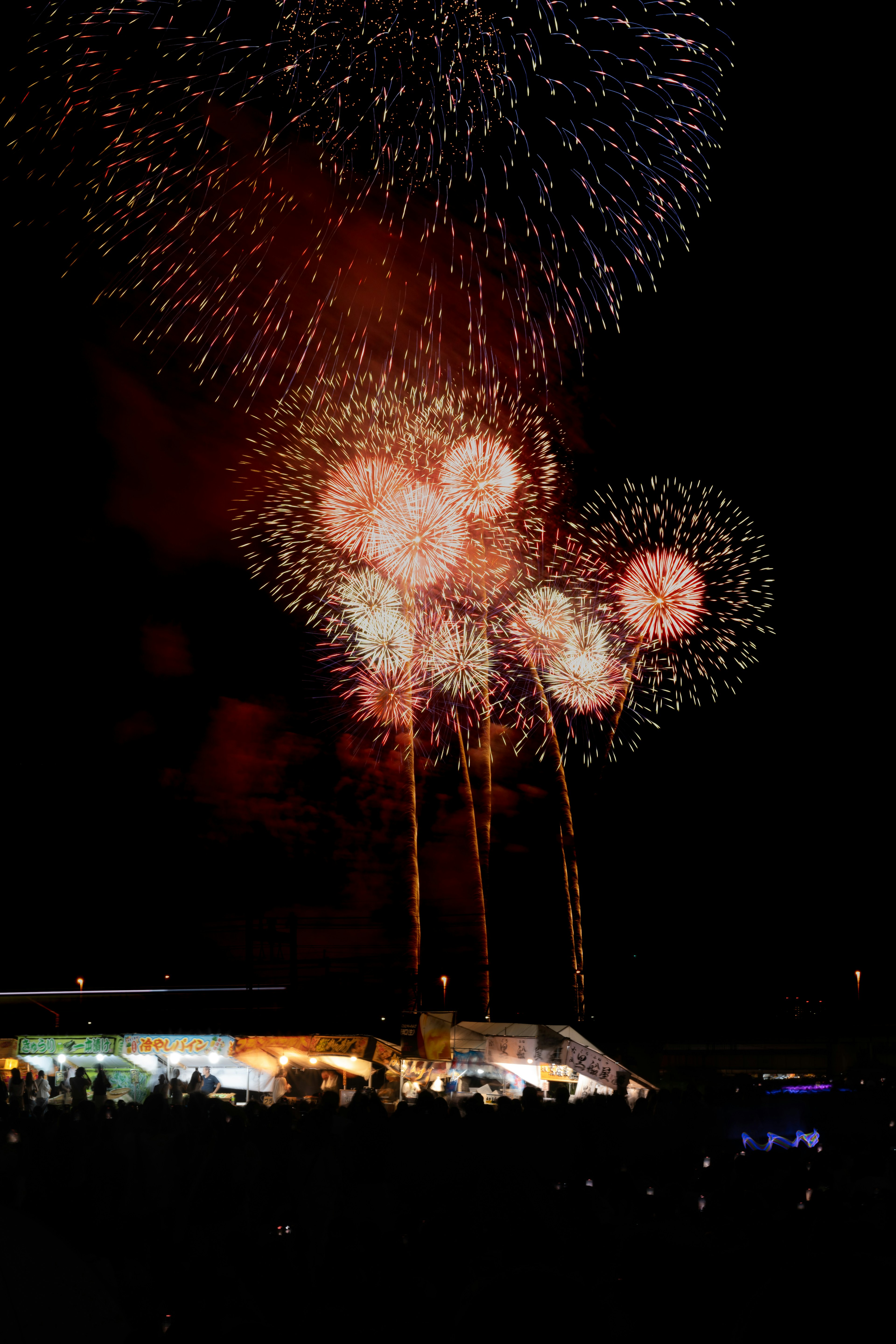 Spectacle de feux d'artifice colorés dans le ciel nocturne avec des silhouettes de spectateurs