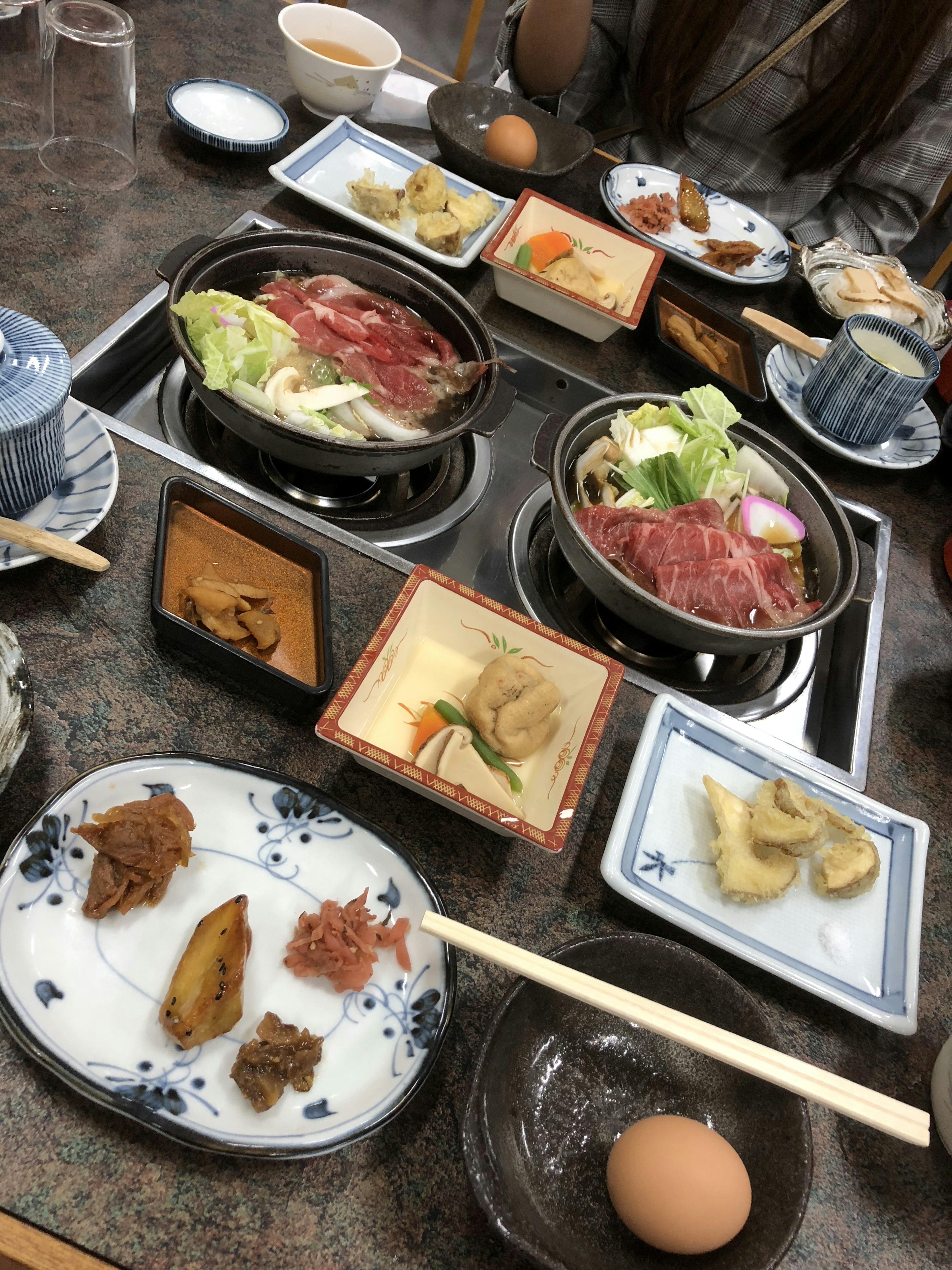 桌子上擺放著日本餐點，包括涮涮鍋、蔬菜、雞蛋和各種配菜