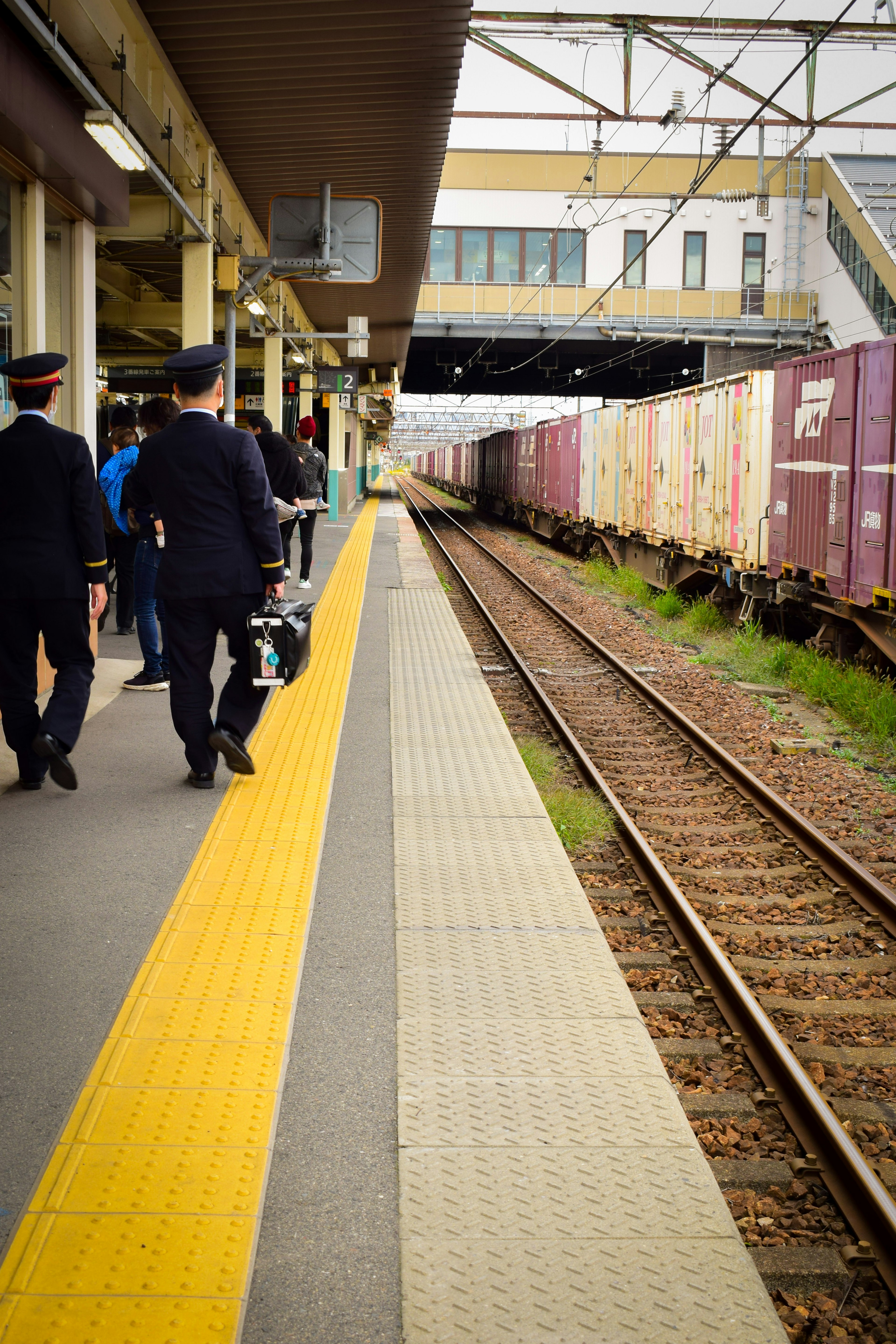 Pemandangan dua pekerja kereta api di platform dengan kereta barang terlihat