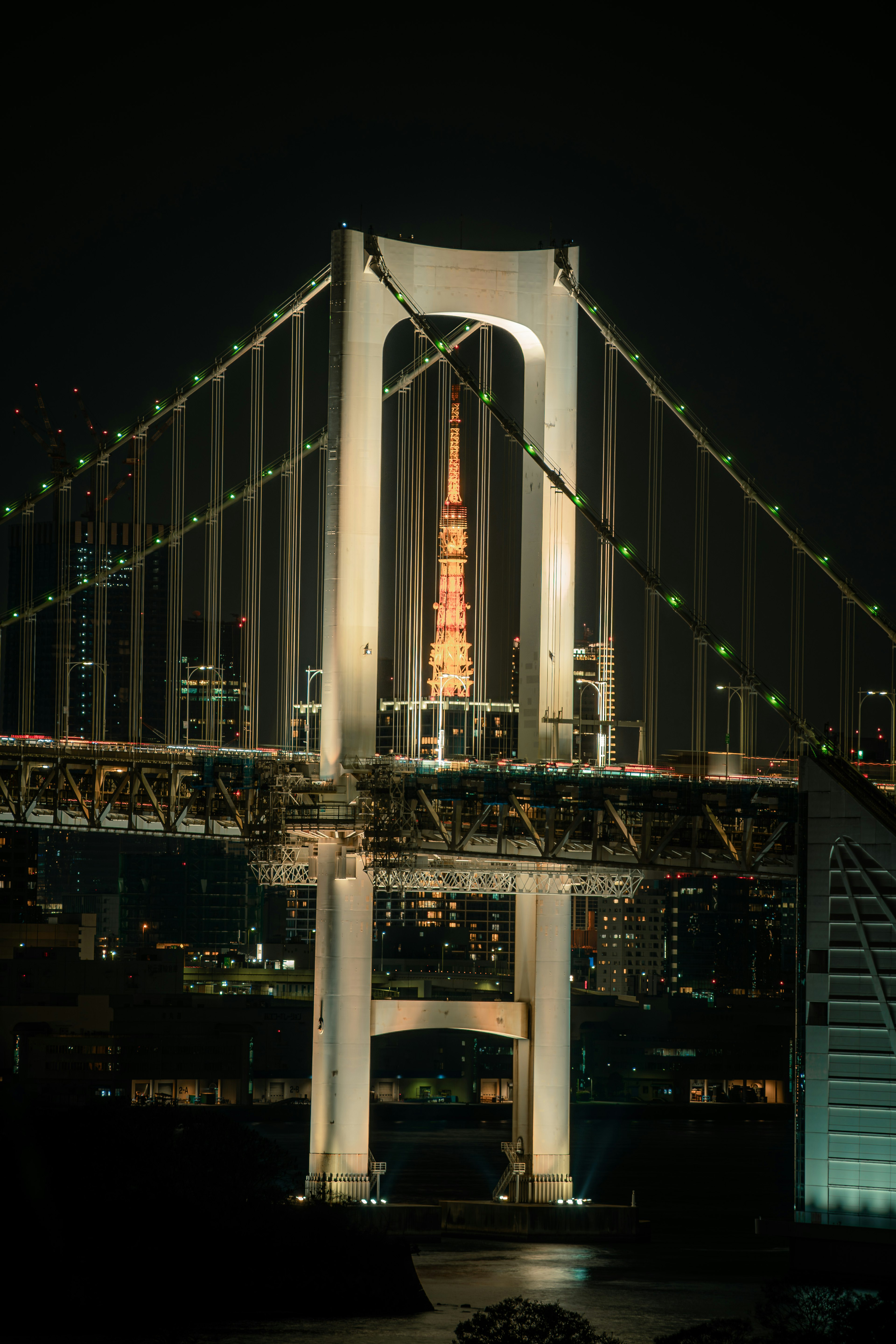 Tokyo Tower visible through the Rainbow Bridge at night