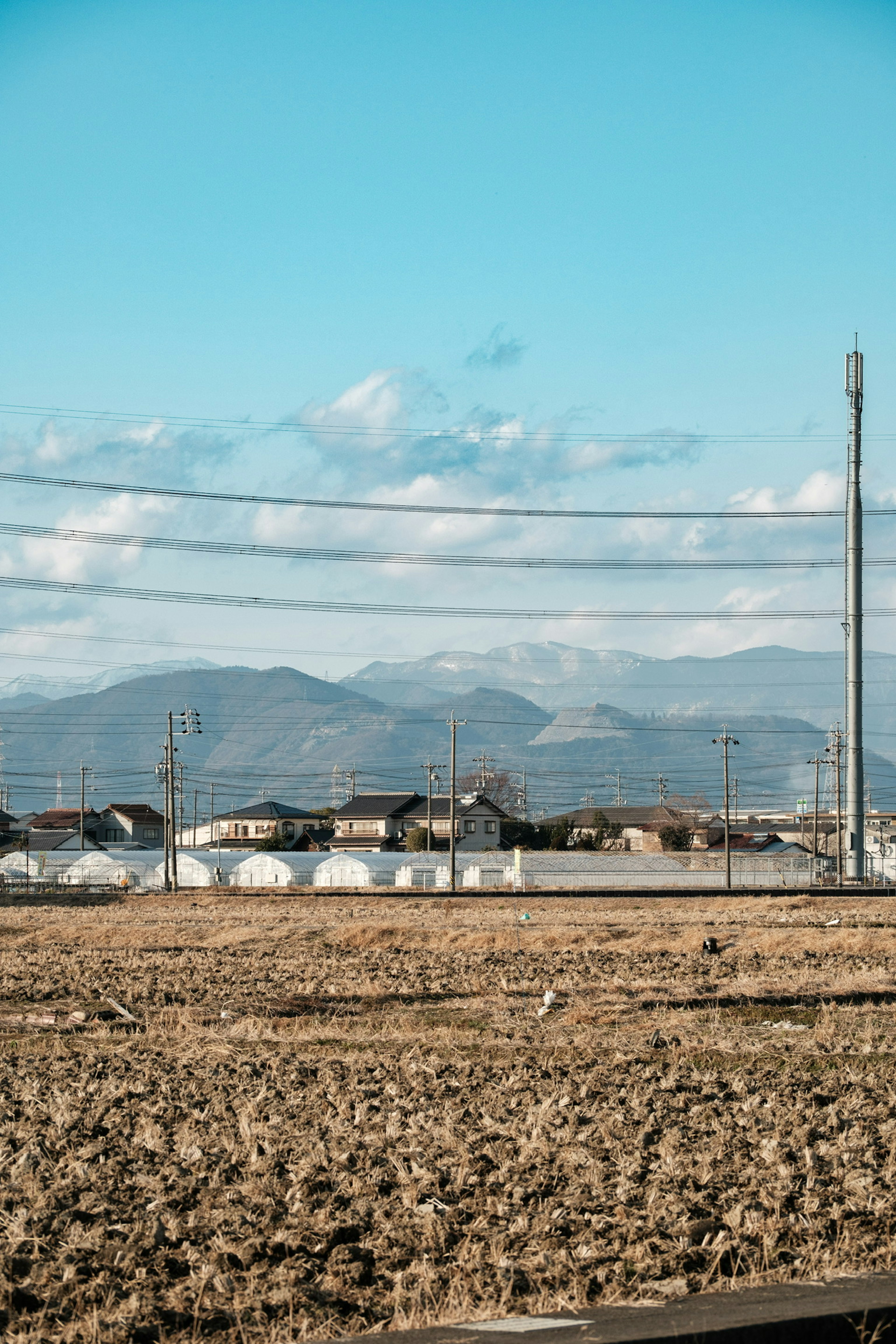 青空と雲の下に広がる田園風景と山々の景色