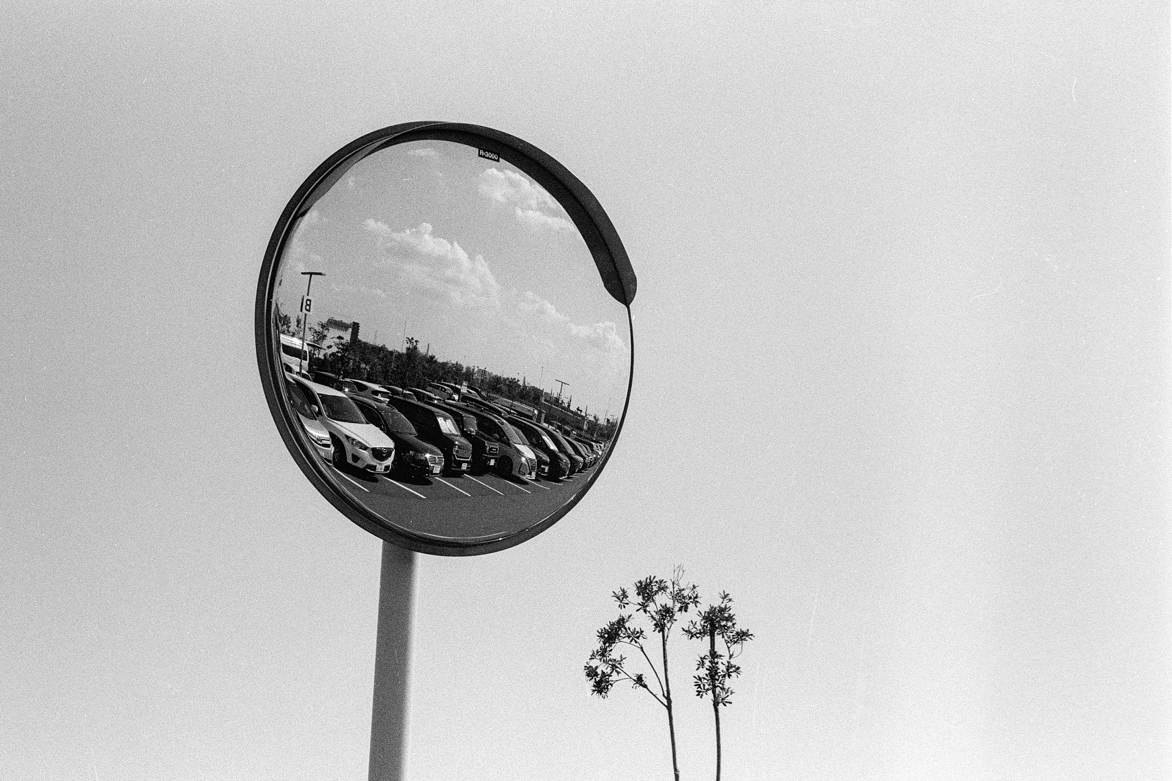 Miroir rond reflétant des voitures garées et un ciel bleu