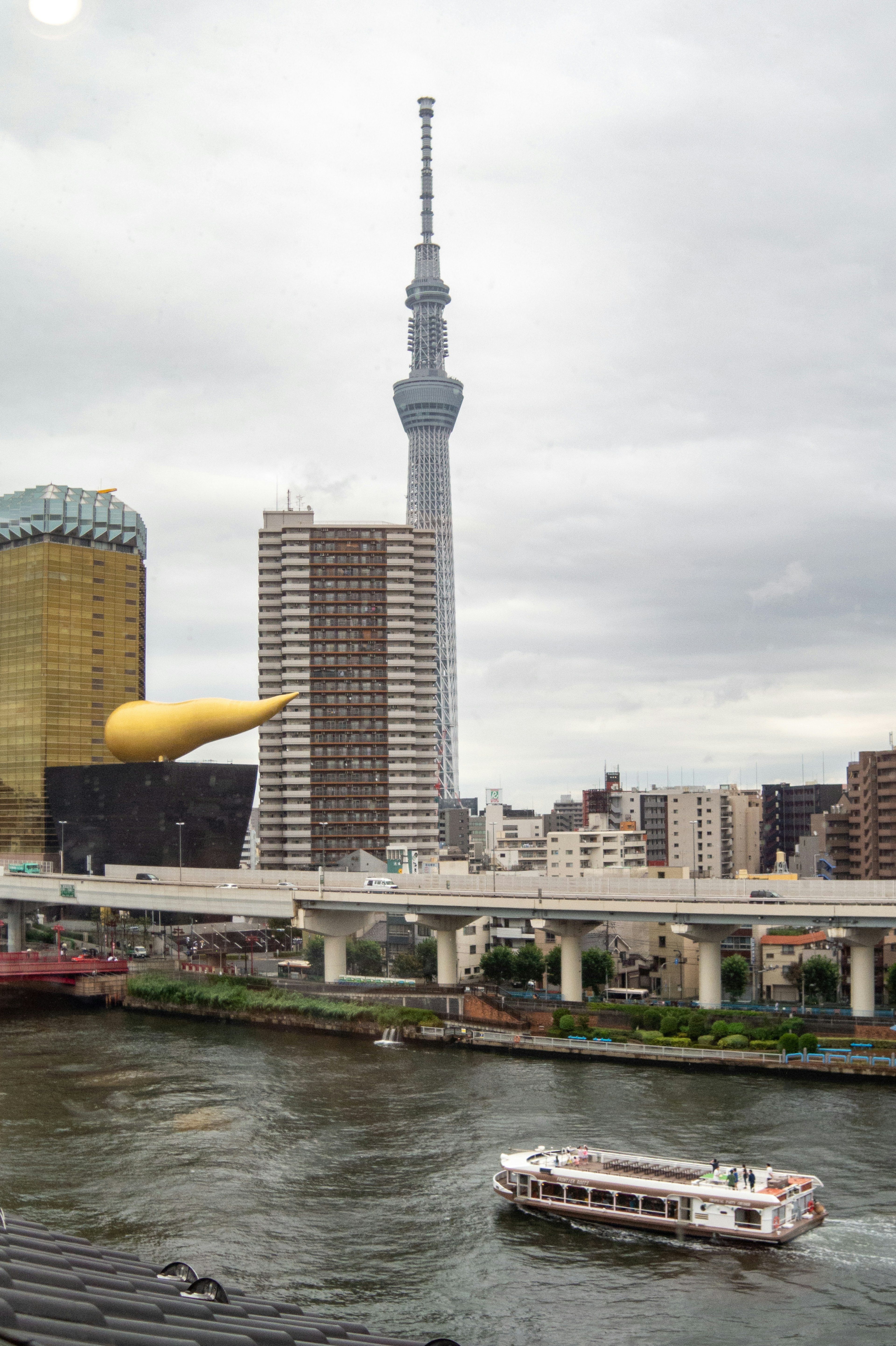 Blick auf den Tokyo Skytree und den Sumida-Fluss mit nahegelegenen Gebäuden und einem Boot